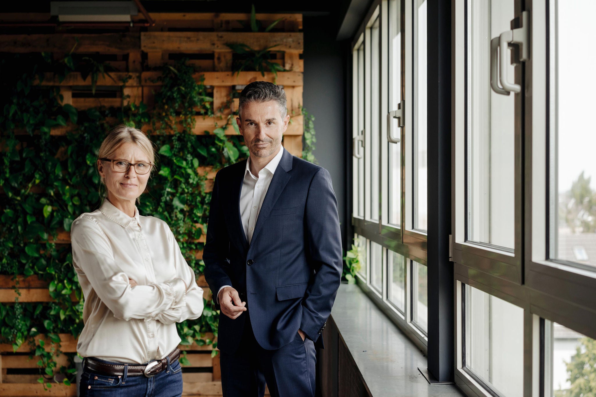 Confident businessman and businesswoman in green office