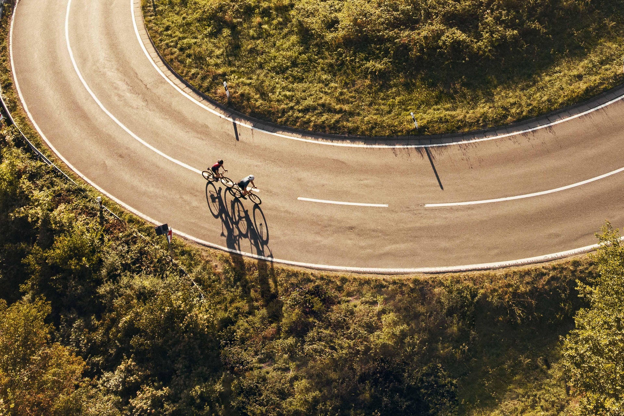 Aerial view on two cyclists on a windy mountain road