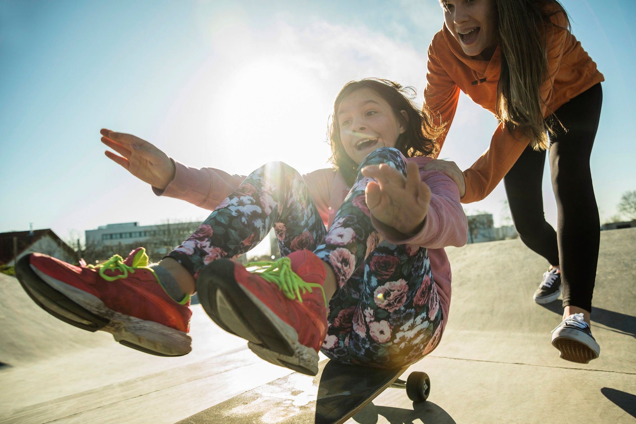 Teenage girl pushing girl on skateboard