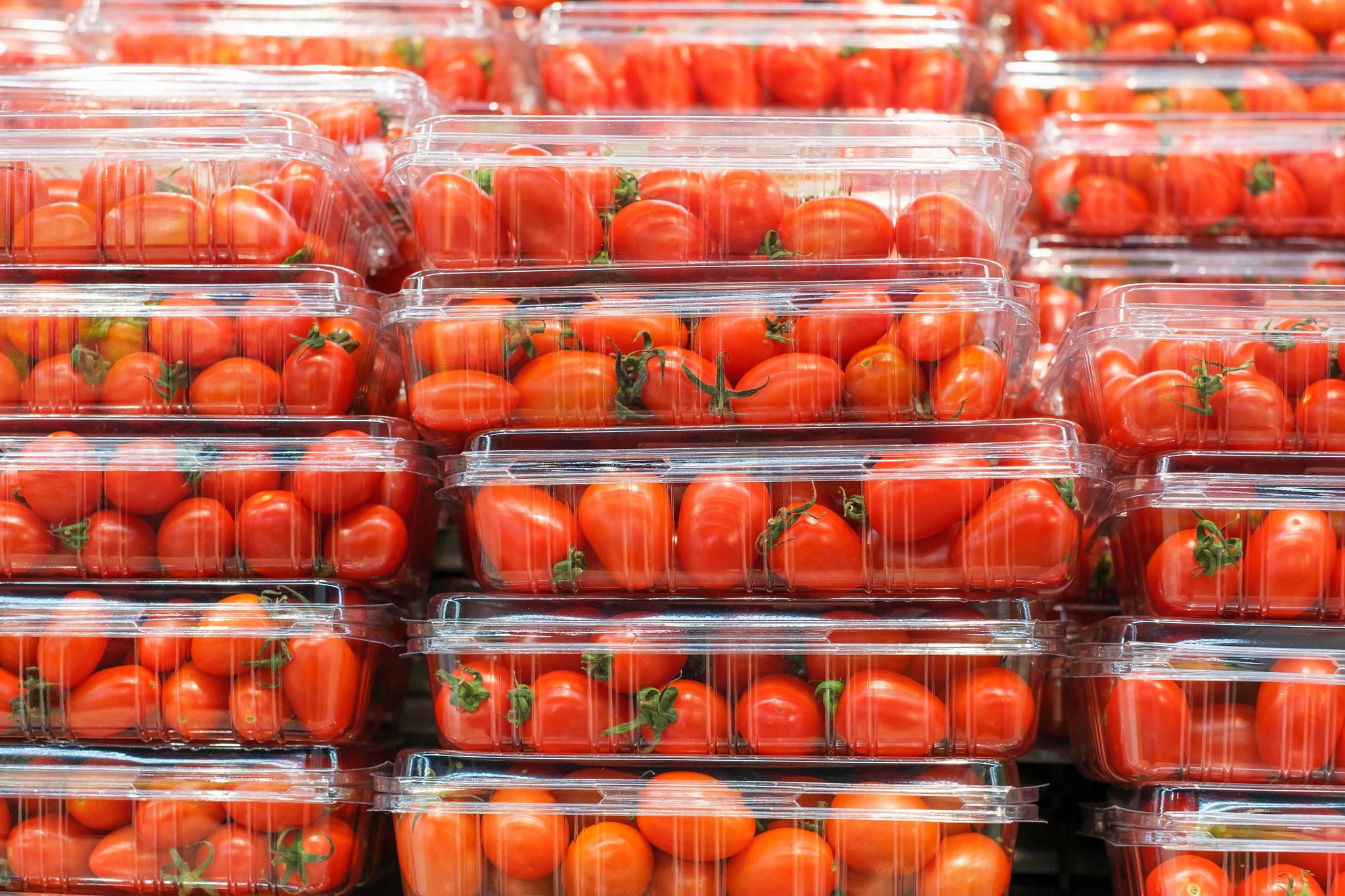 Stacks of red cherry tomatoes in plastic containers