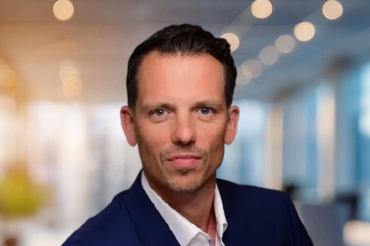 Eine Person im blauen Anzug sitzt in modernem Büro, umgeben von warmen Lichtpunkten im Hintergrund