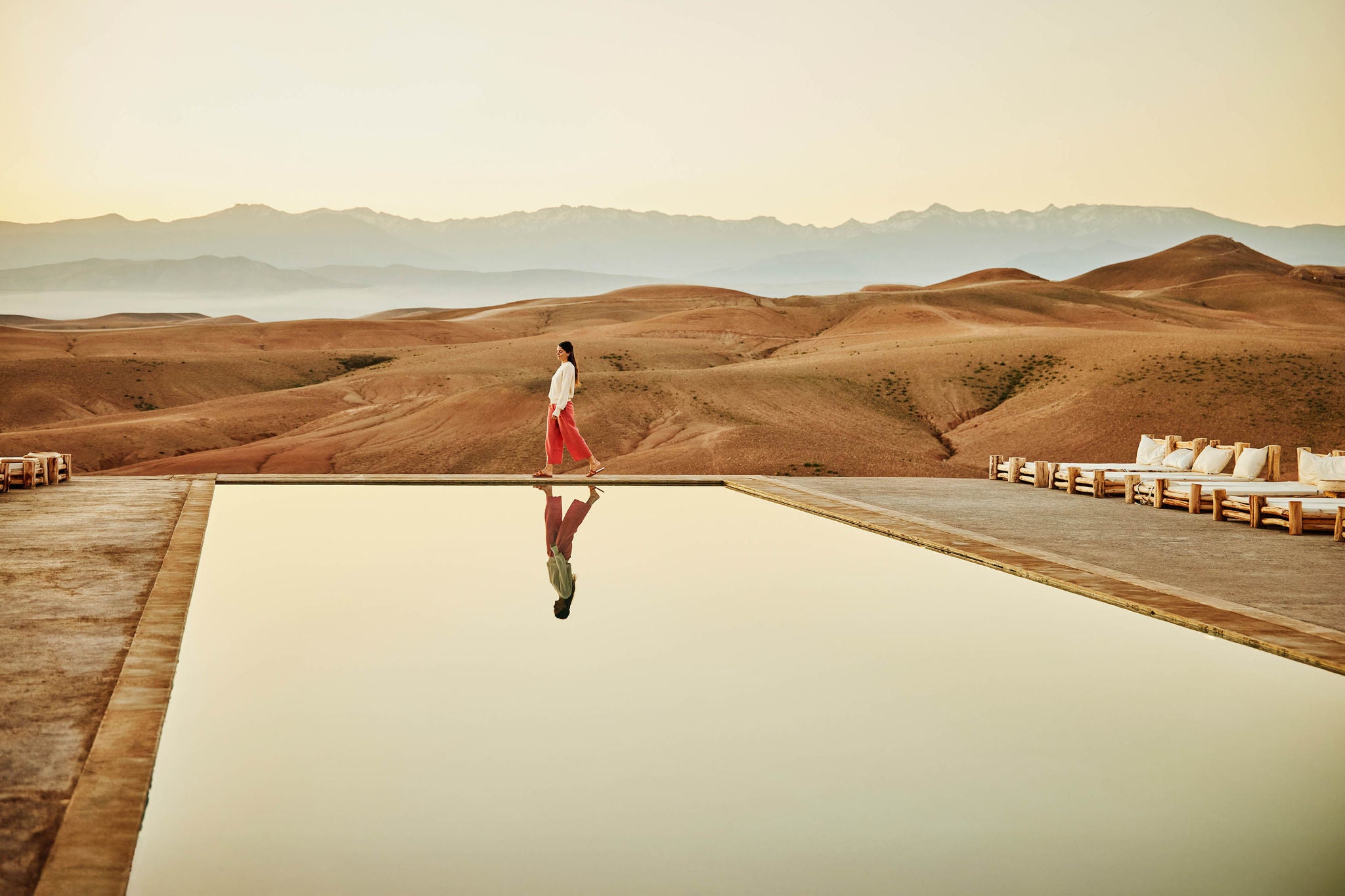 Extreme wide shot woman walking poolside at luxury desert camp