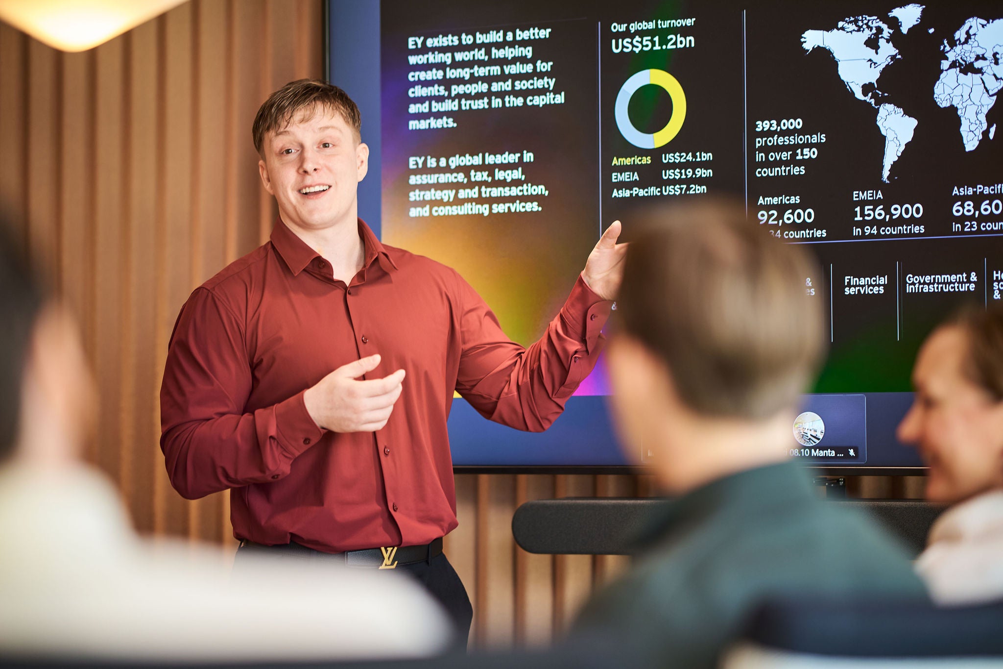 Nuori mies pitämässä esitystä neuvotteluhuoneessa