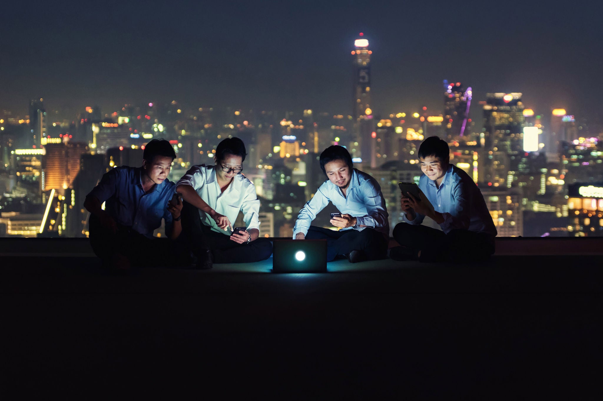 Group of businesspeople working on a rooftop at night