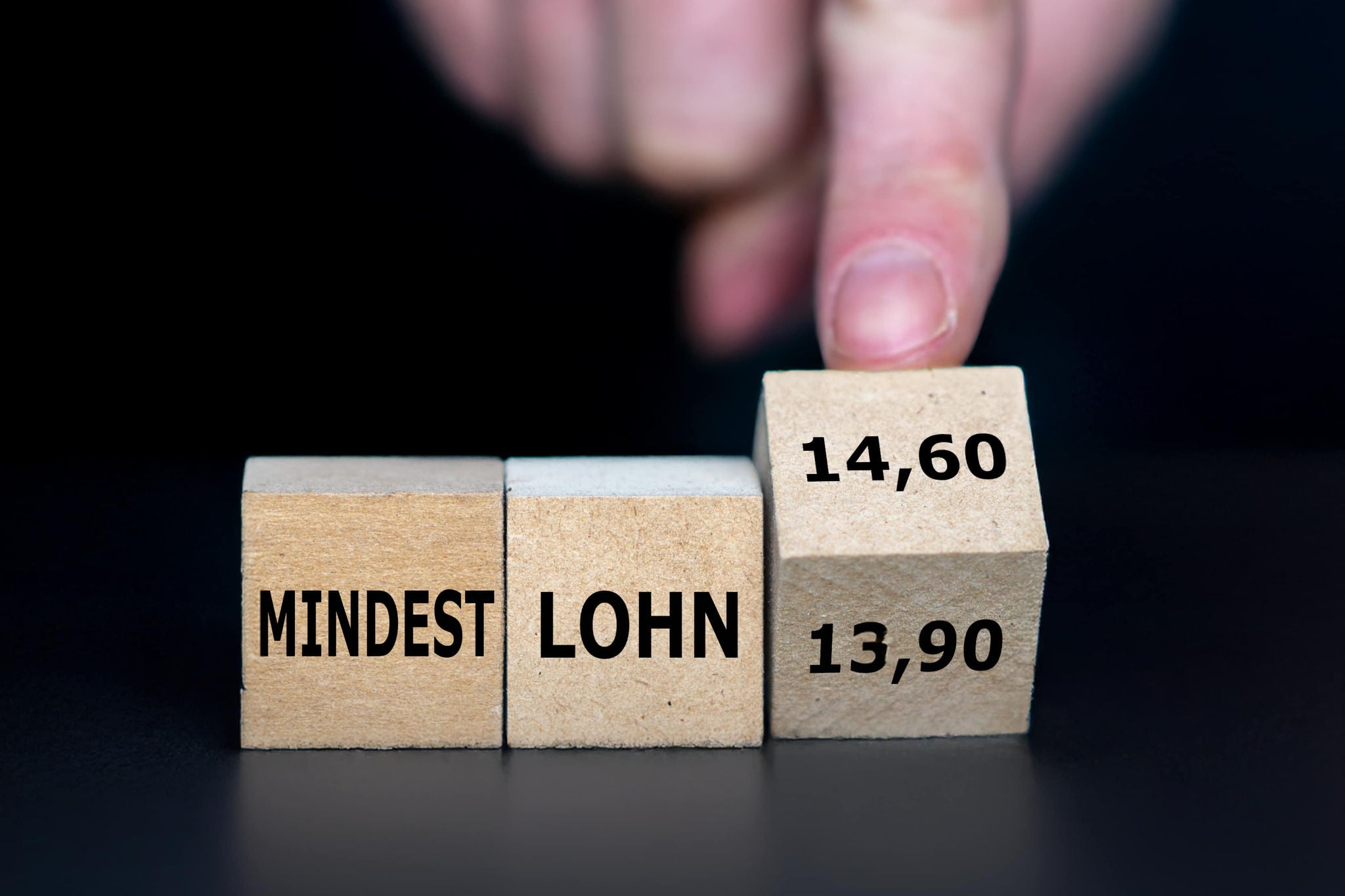 A smiling young woman with headphones and folders, standing outdoors on a college campus.