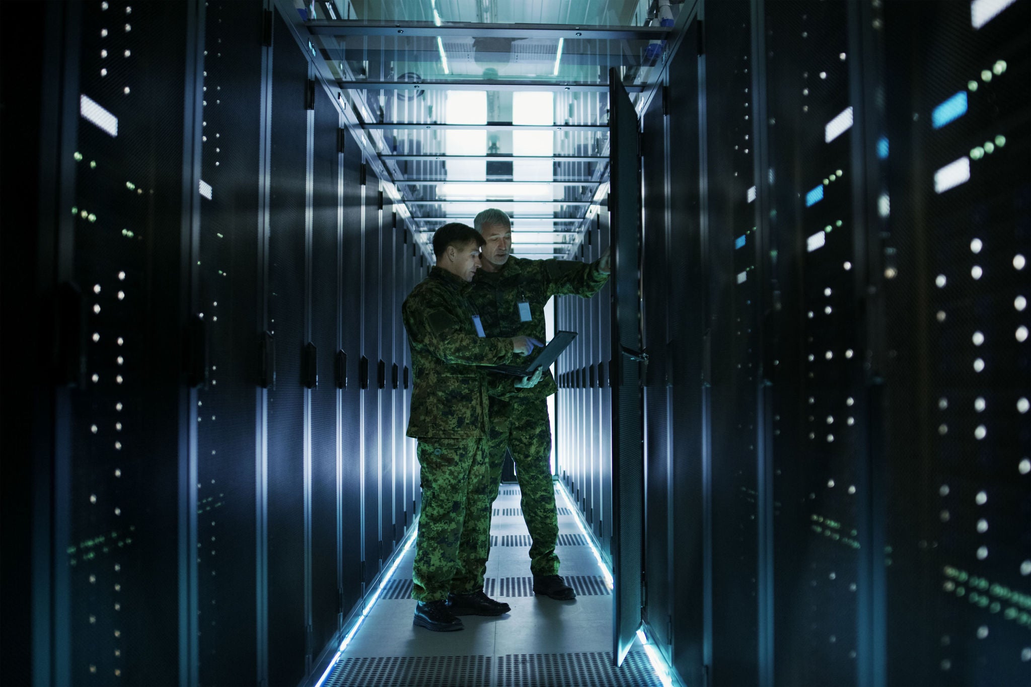 Two personnel inspecting server racks in a data center,