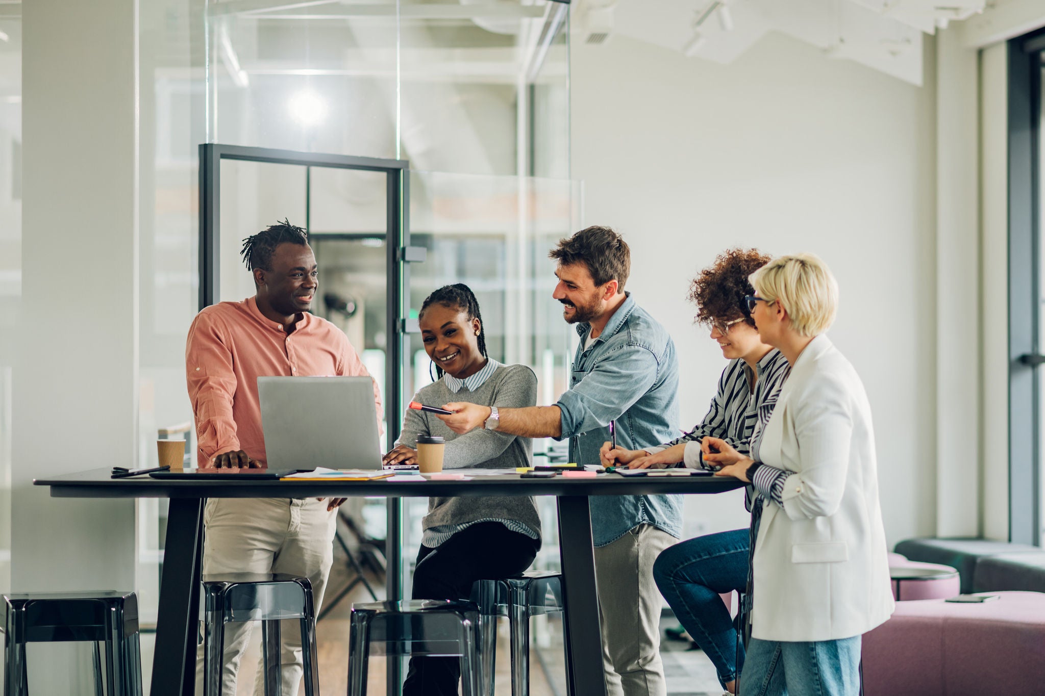 Diverse employees gathered in the office having fun during brainstorming while discussing new ideas for their new project. Multiracial coworkers gather in boardroom discuss ideas in group at briefing.
