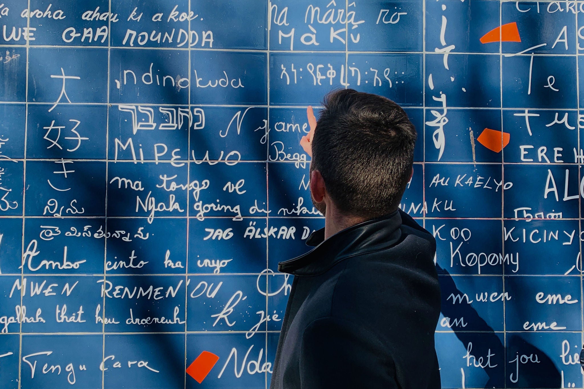 Person pointing at a blue board filled with handwritten symbols
