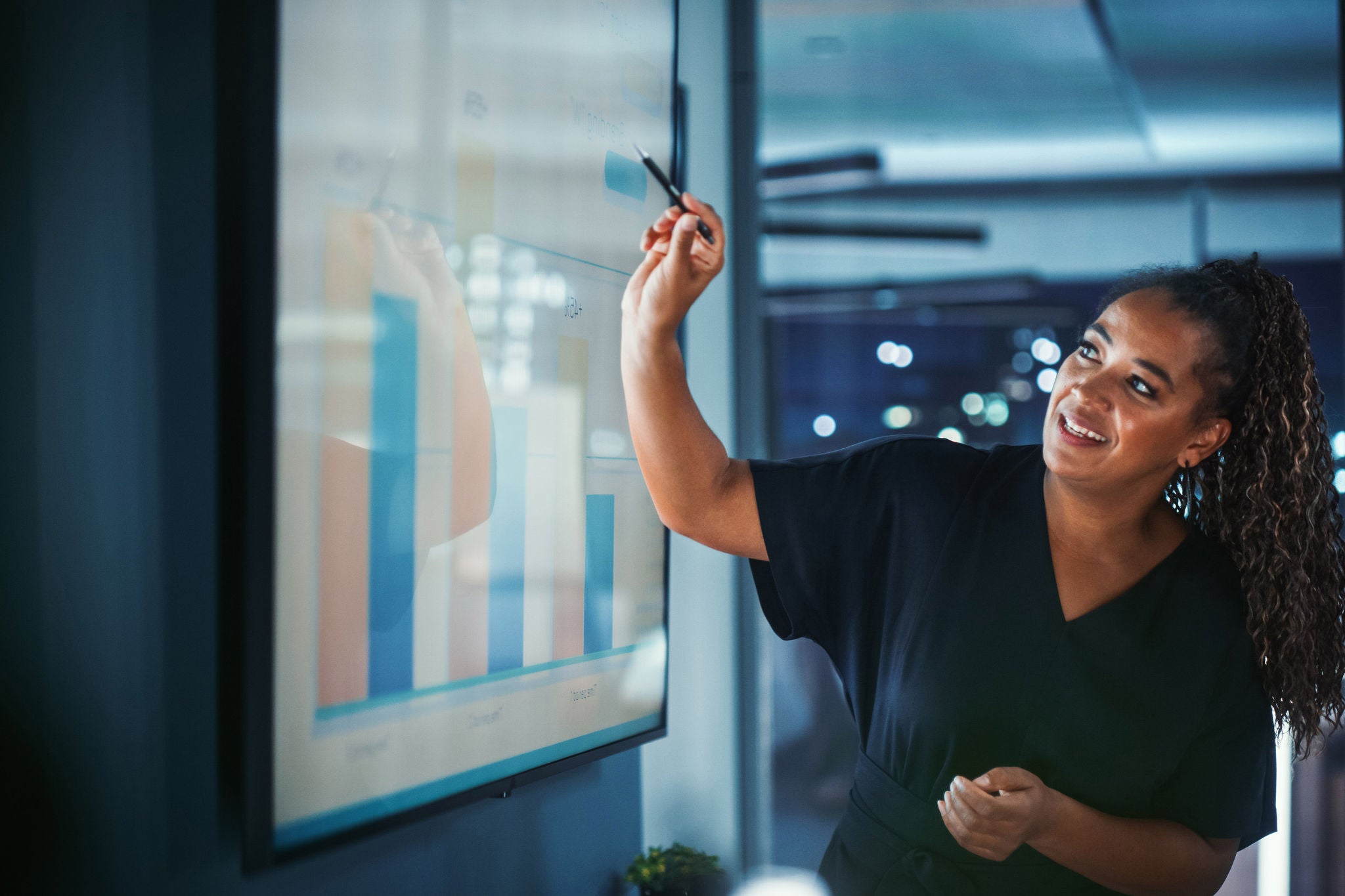 Der Betriebsleiter des Unternehmens hält eine Präsentation für Mitarbeiter und Führungskräfte ab. Kreative schwarze Frau verwendet TV-Bildschirm mit Wachstumsanalyse; Diagramme; Werbeeinnahmen. Arbeit im Geschäftsbüro.