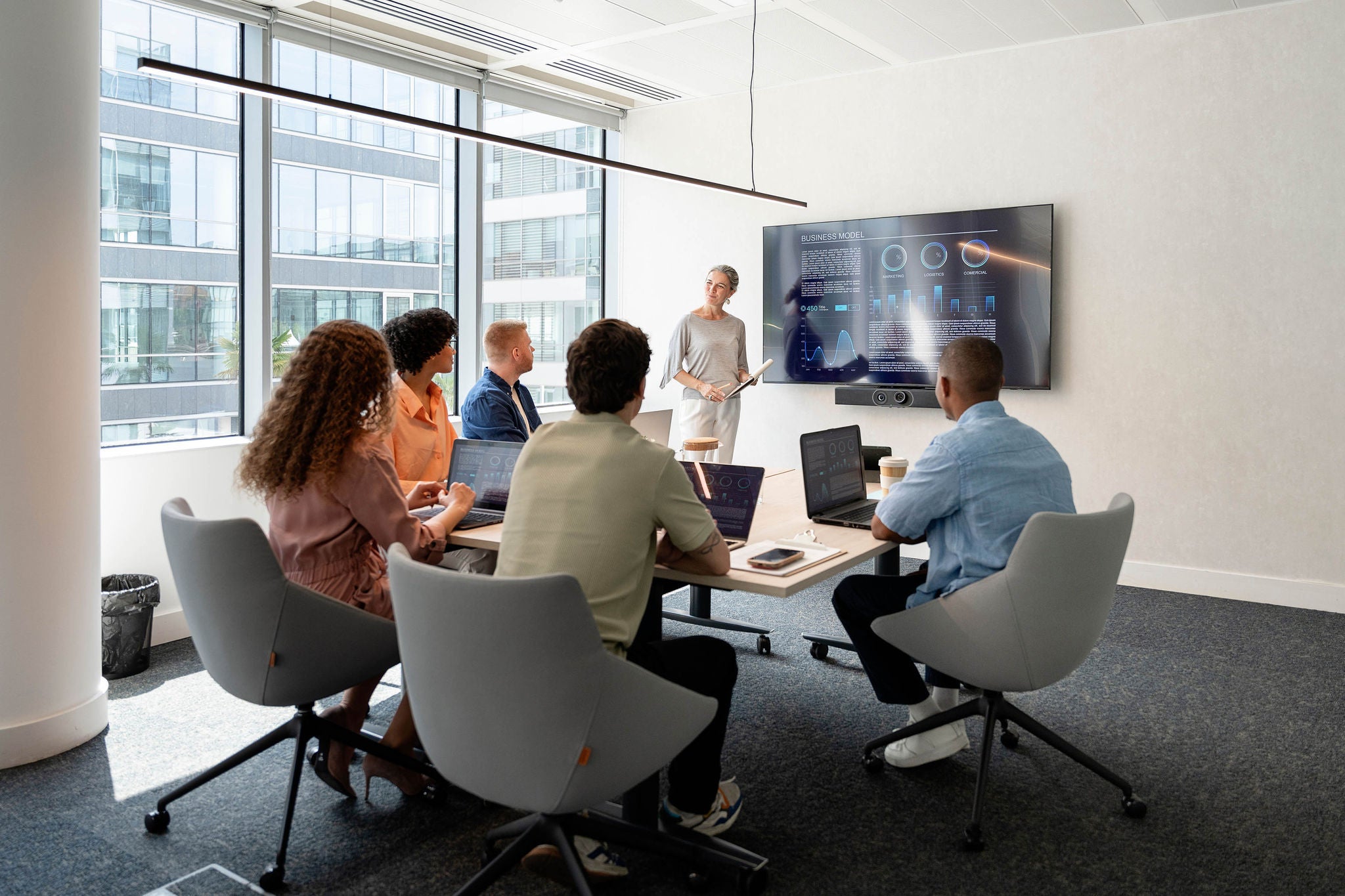 Businesspeople analyzing charts displayed on a large screen during a productive meeting