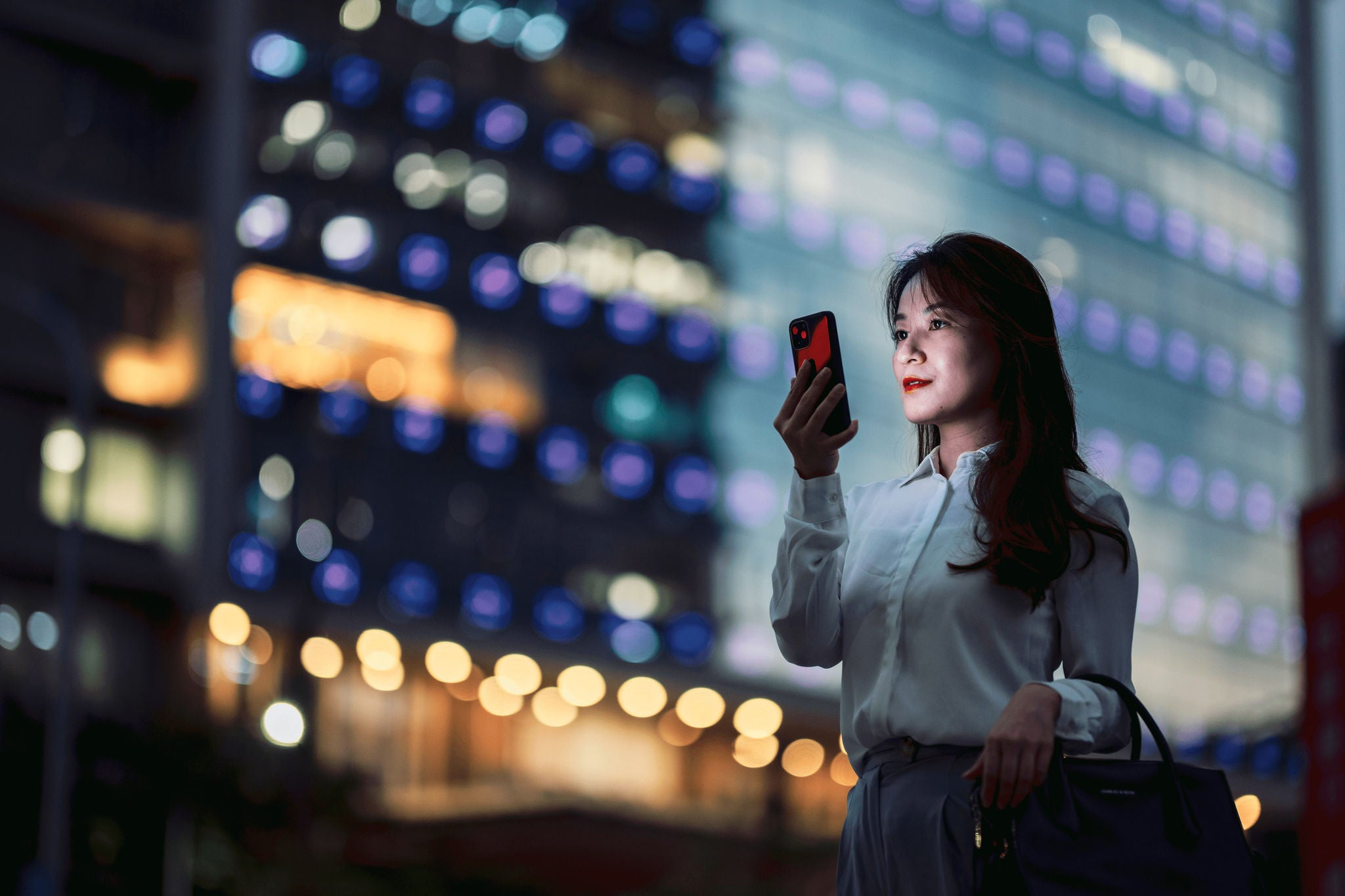 ey-woman-watching-phone-infront-of-a-building
