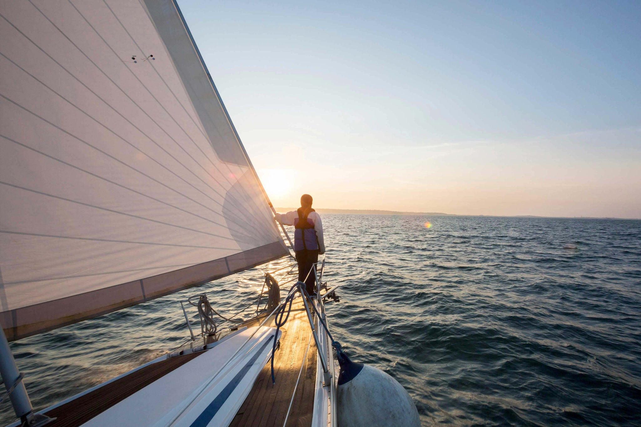 Mann auf Segelboot bei Sonnenuntergang
