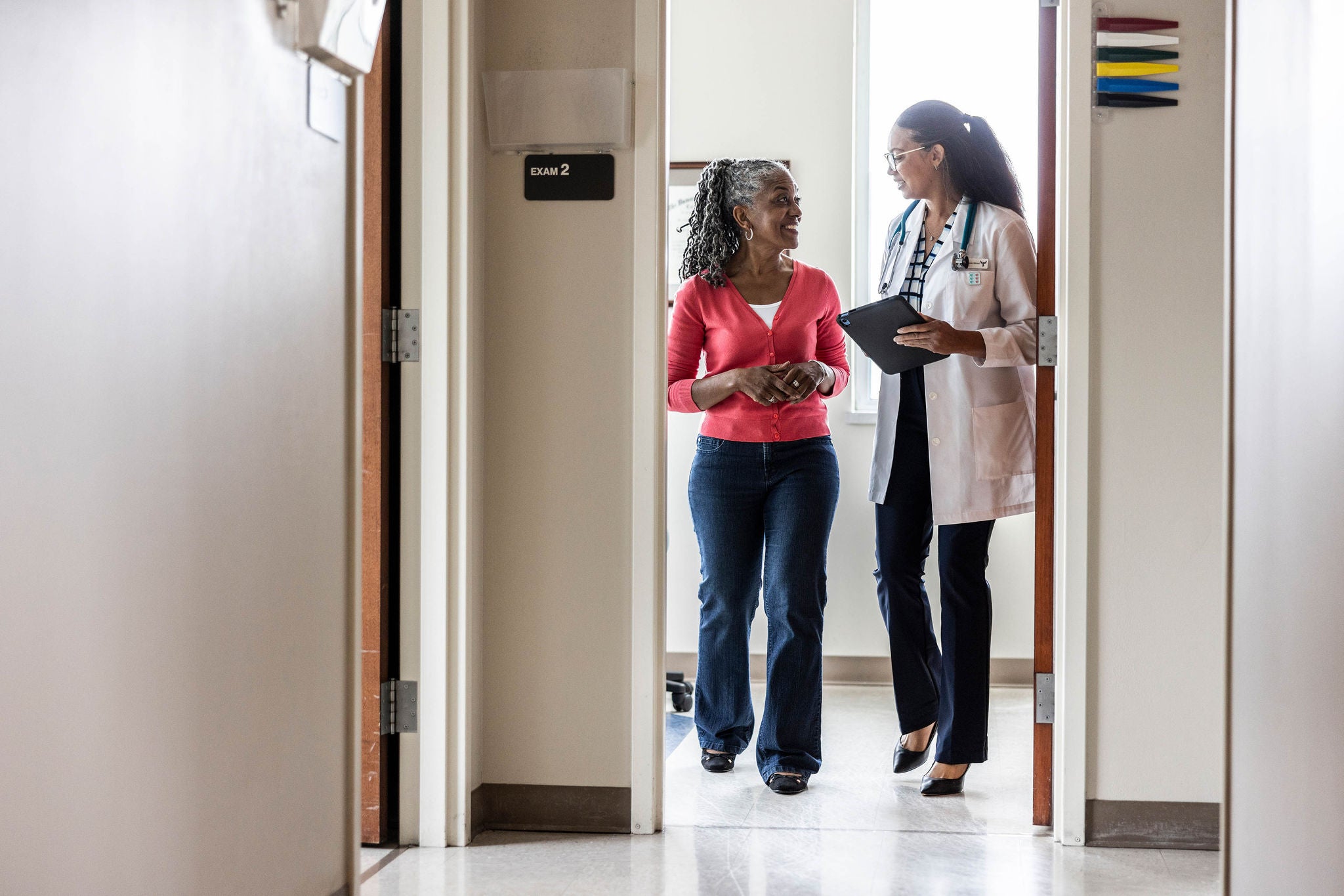 Female doctor talking with senior woman in doctor's office hallway