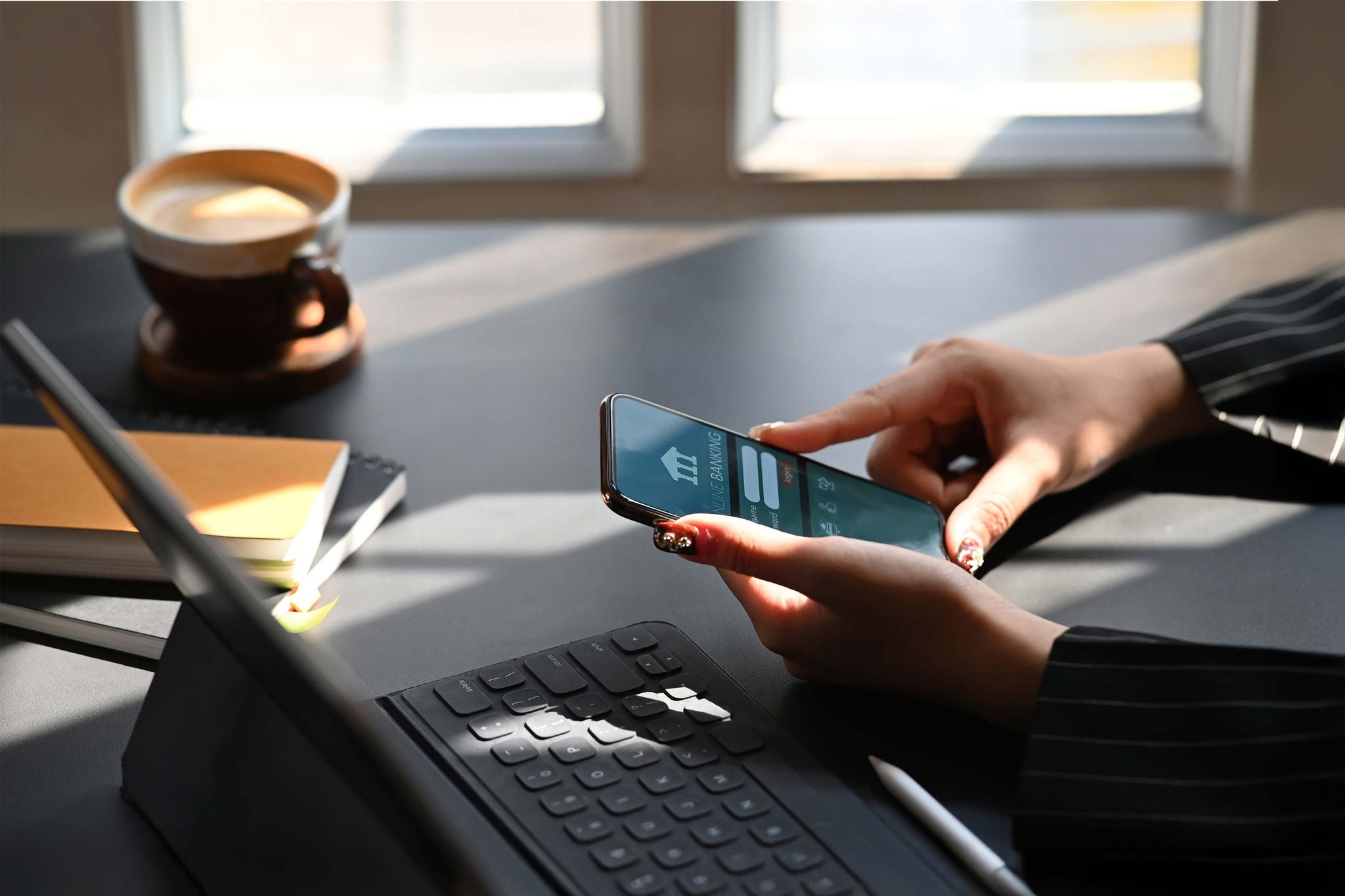 Smartphone mit Banking‑App neben Tastatur und Kaffee