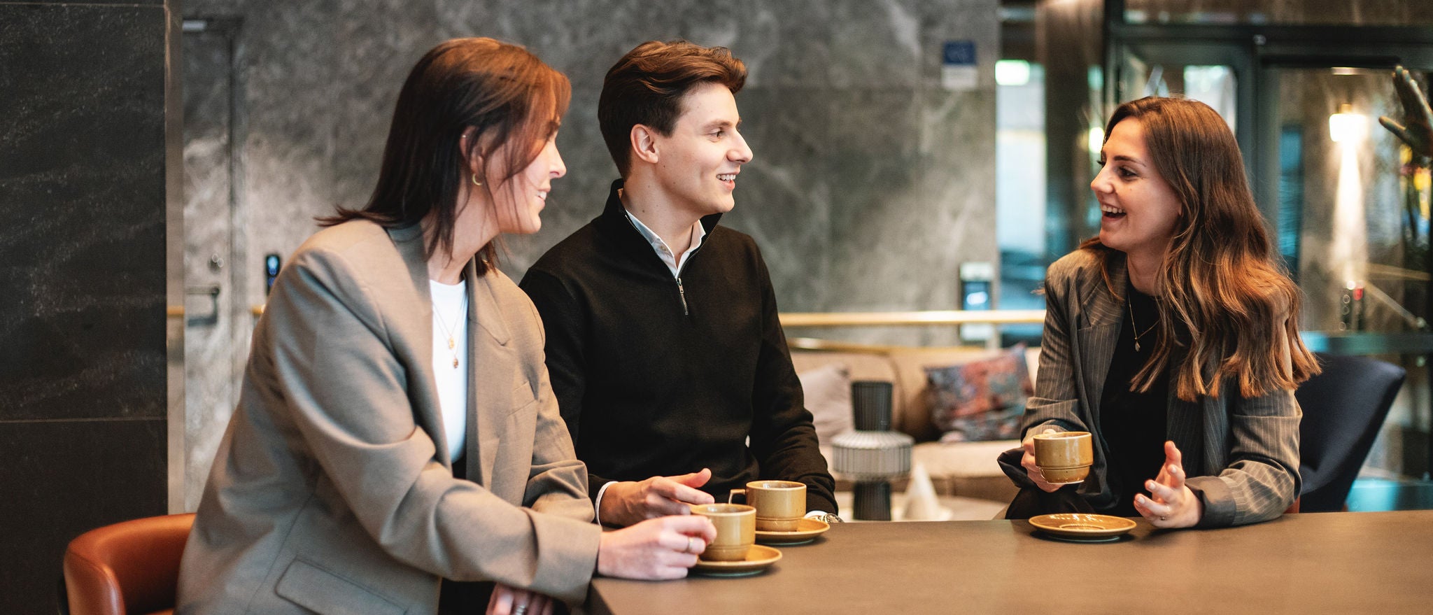 Team discussing ideas over coffee in modern office lounge setting