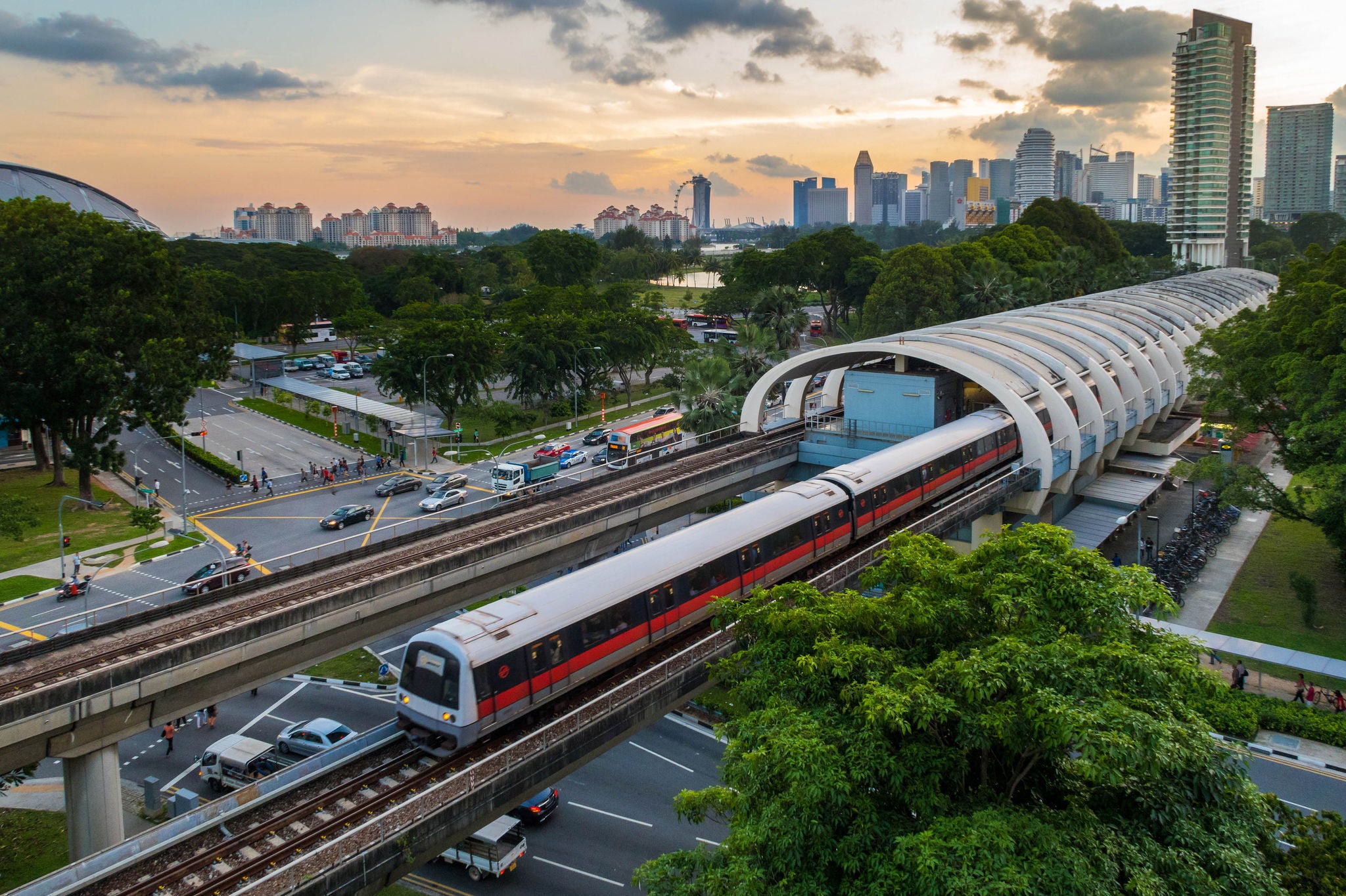A high view point of Singapore mass rapid transit  (MRT) transportation train service in central Kallang station during sunset with Singapore city skyline in background. Singapore MRT train system serves as one of Singapore daily transportation for most commuters. Background include Singapore downtown city skyline with modern skyscrapers and commercial buildings such as Marina Bay Sands and Singapore flyer