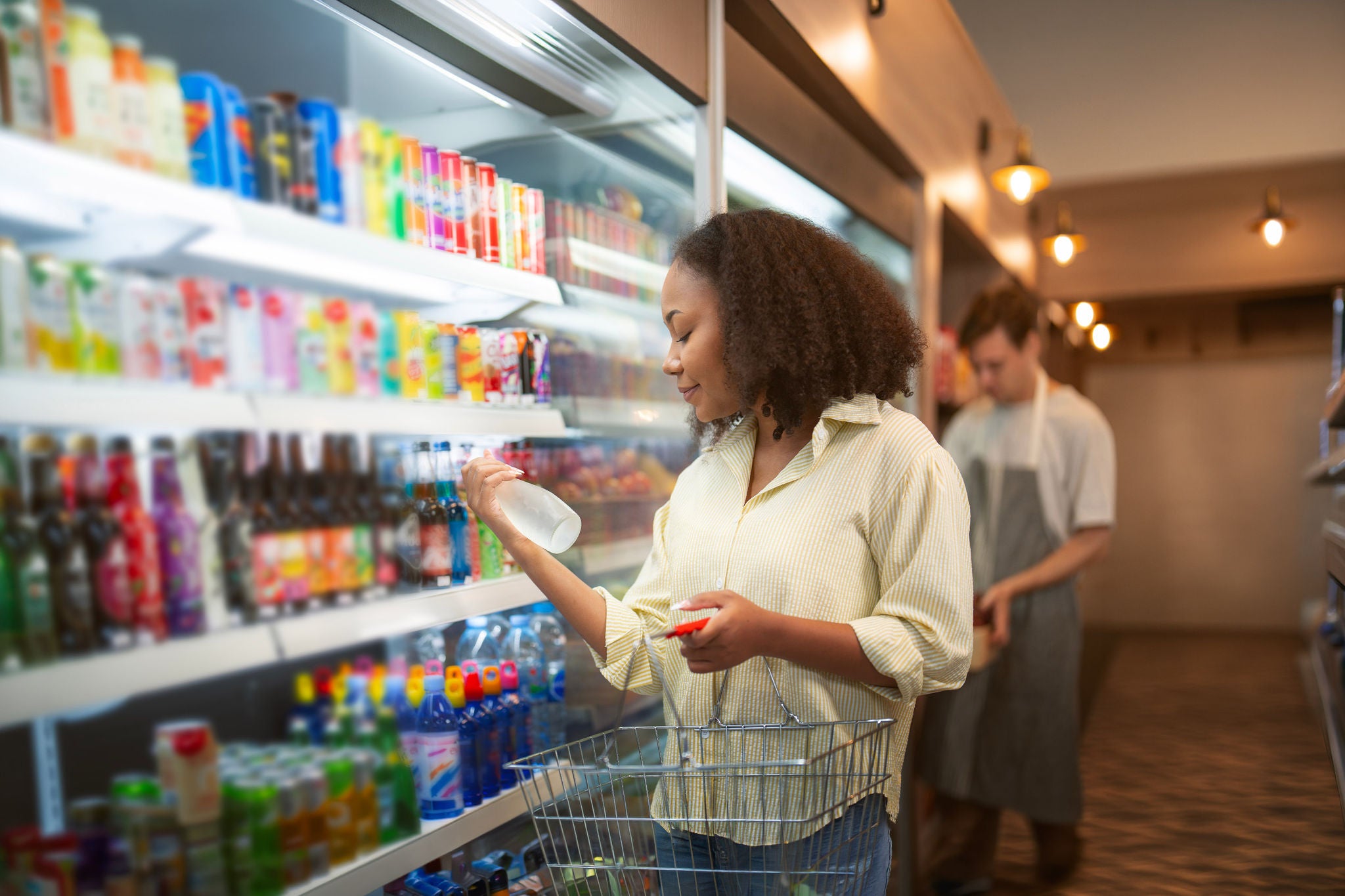 An African american woman buy a bottle of milk from refrigerator cold in convenience store for drink at home