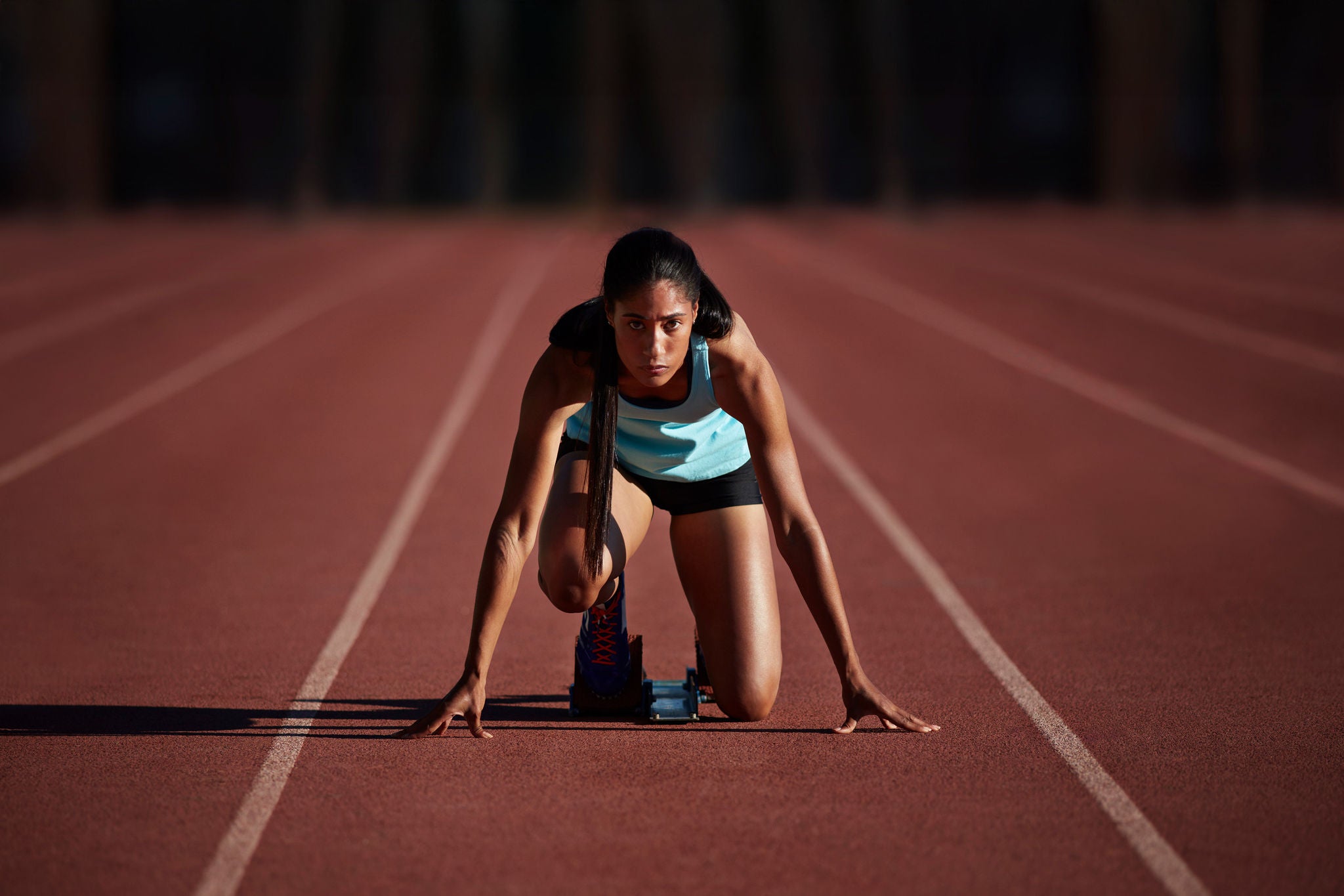 Portrait of female runner getting ready at the start block