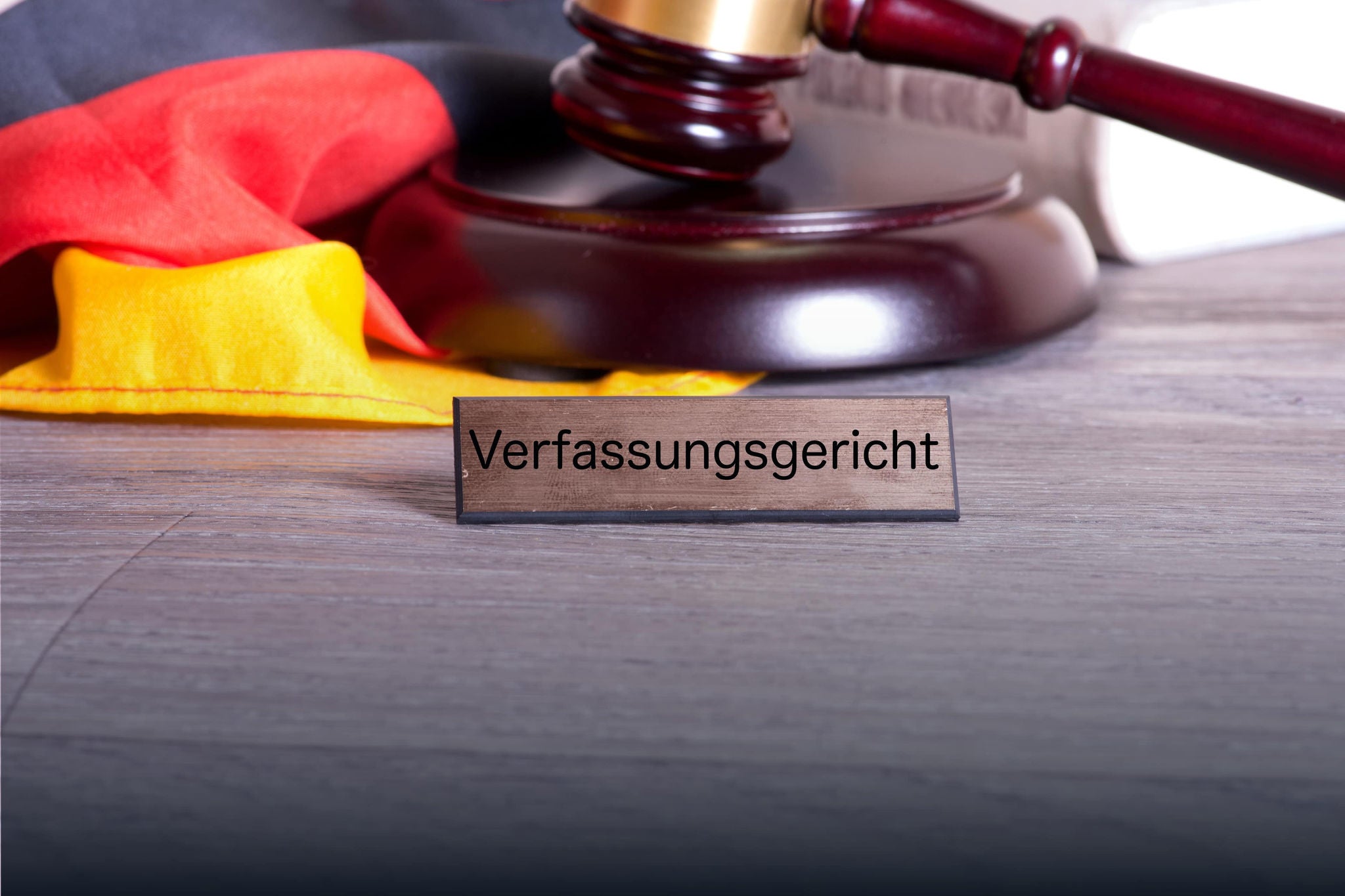 A smiling young woman with headphones and folders, standing outdoors on a college campus.