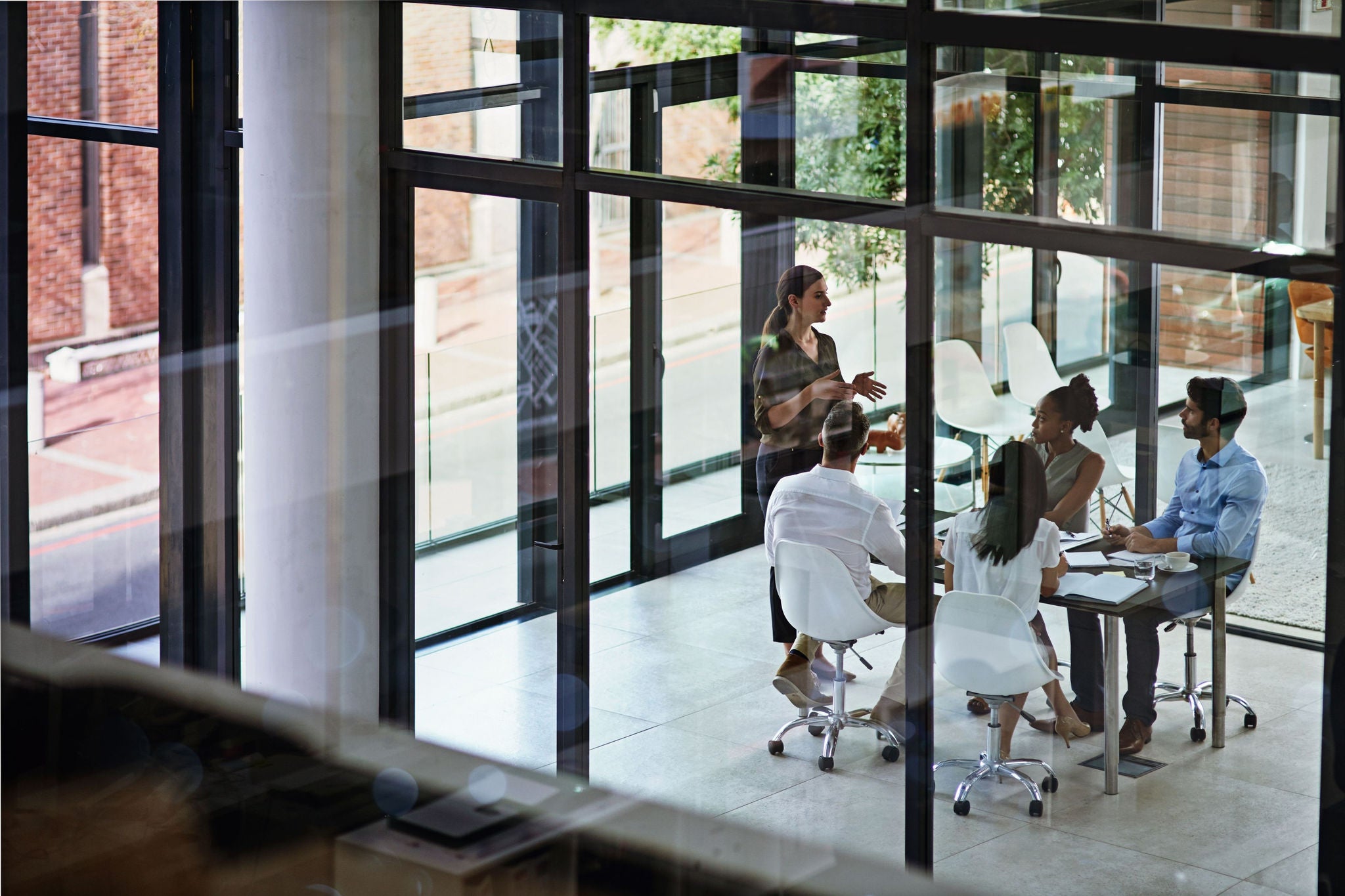 Team members collaborating in a bright, glass-enclosed meeting room