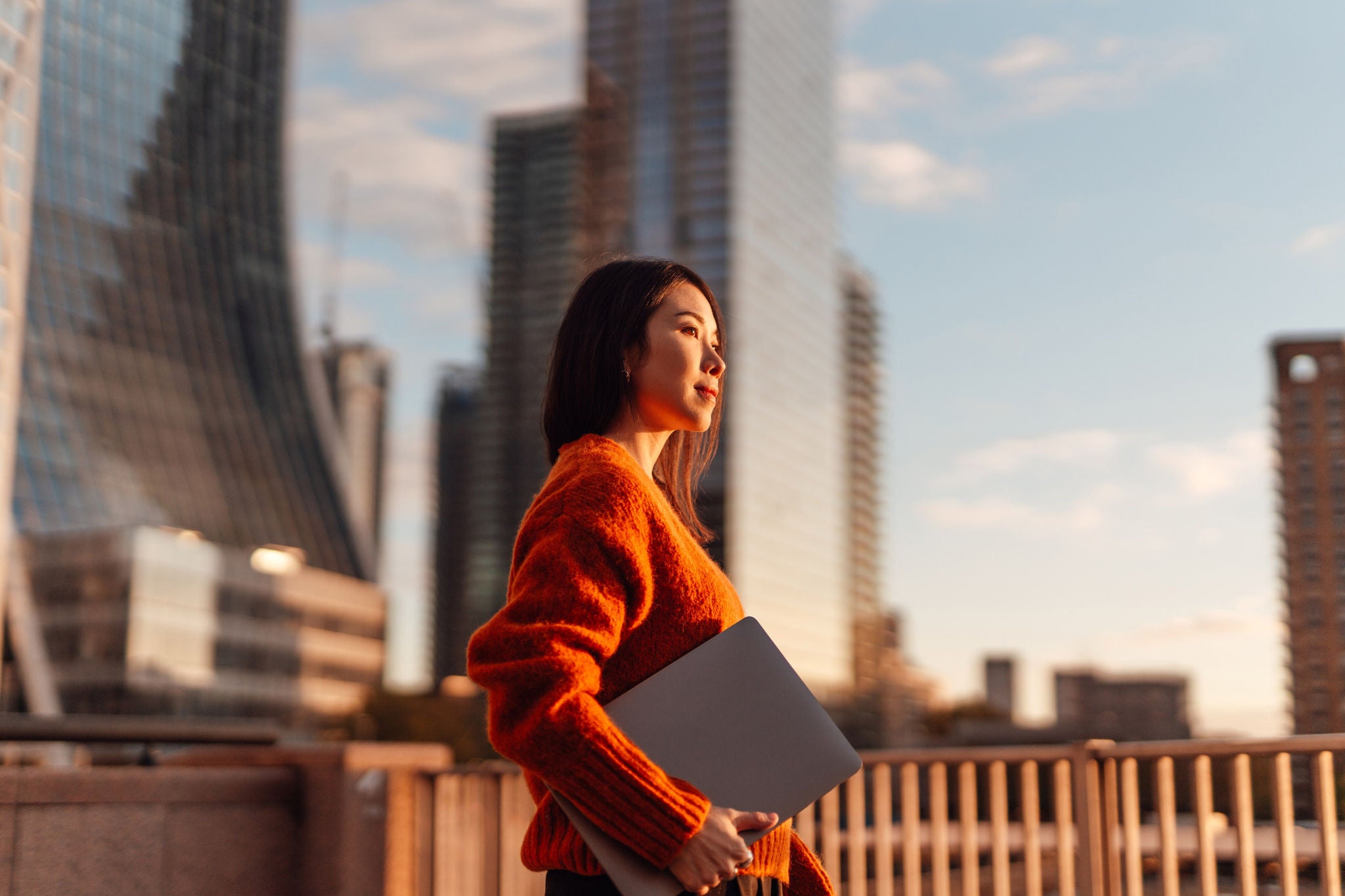 Confident young Asian businesswoman with laptop walking