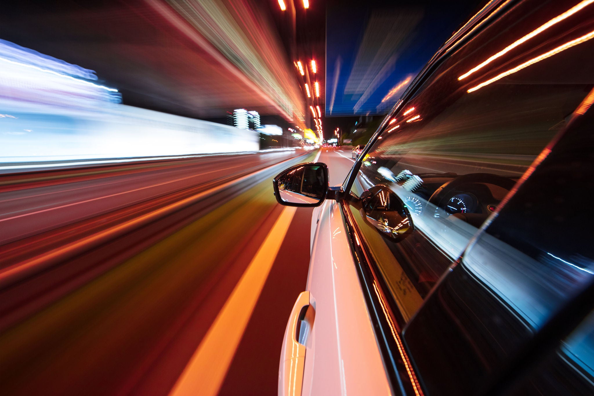 View from side of car moving in a modern night city, blurred motion with lights and cars.