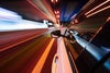 View from side of car moving in a modern night city, blurred motion with lights and cars.
