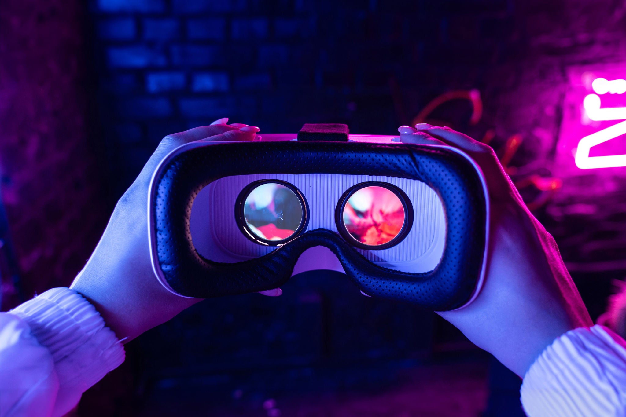 Female hands hold 3d 360 vr headset wear ar innovative glasses goggles on camera in futuristic purple neon light, girl gamer virtual augmented reality technology background concept, close up view