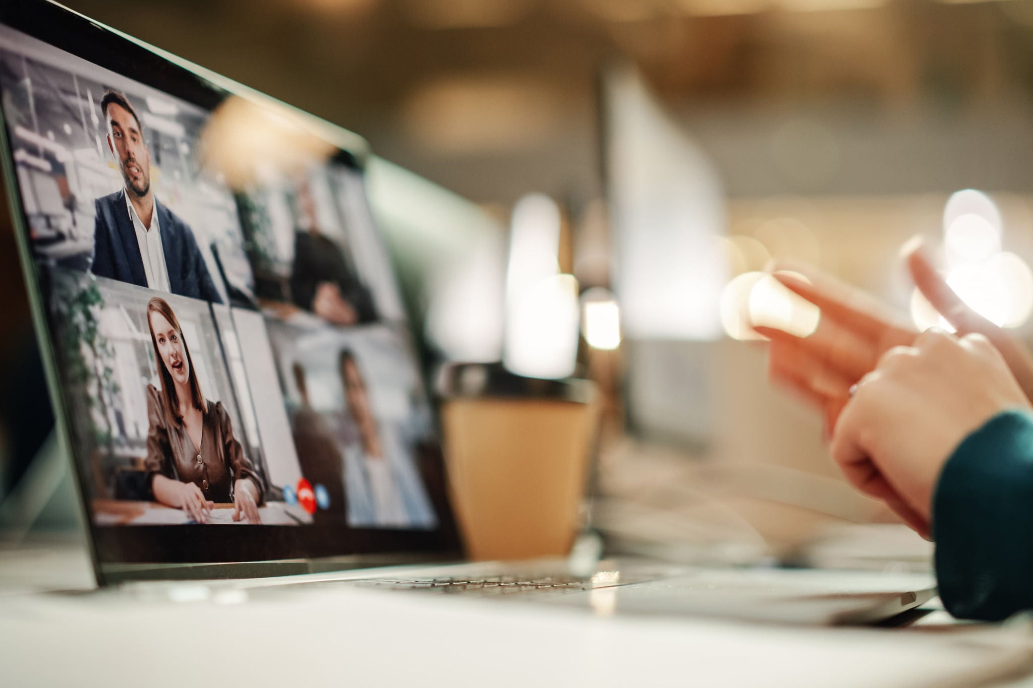 Online-Meeting auf einem Laptop mit mehreren Teilnehmenden im Büro.