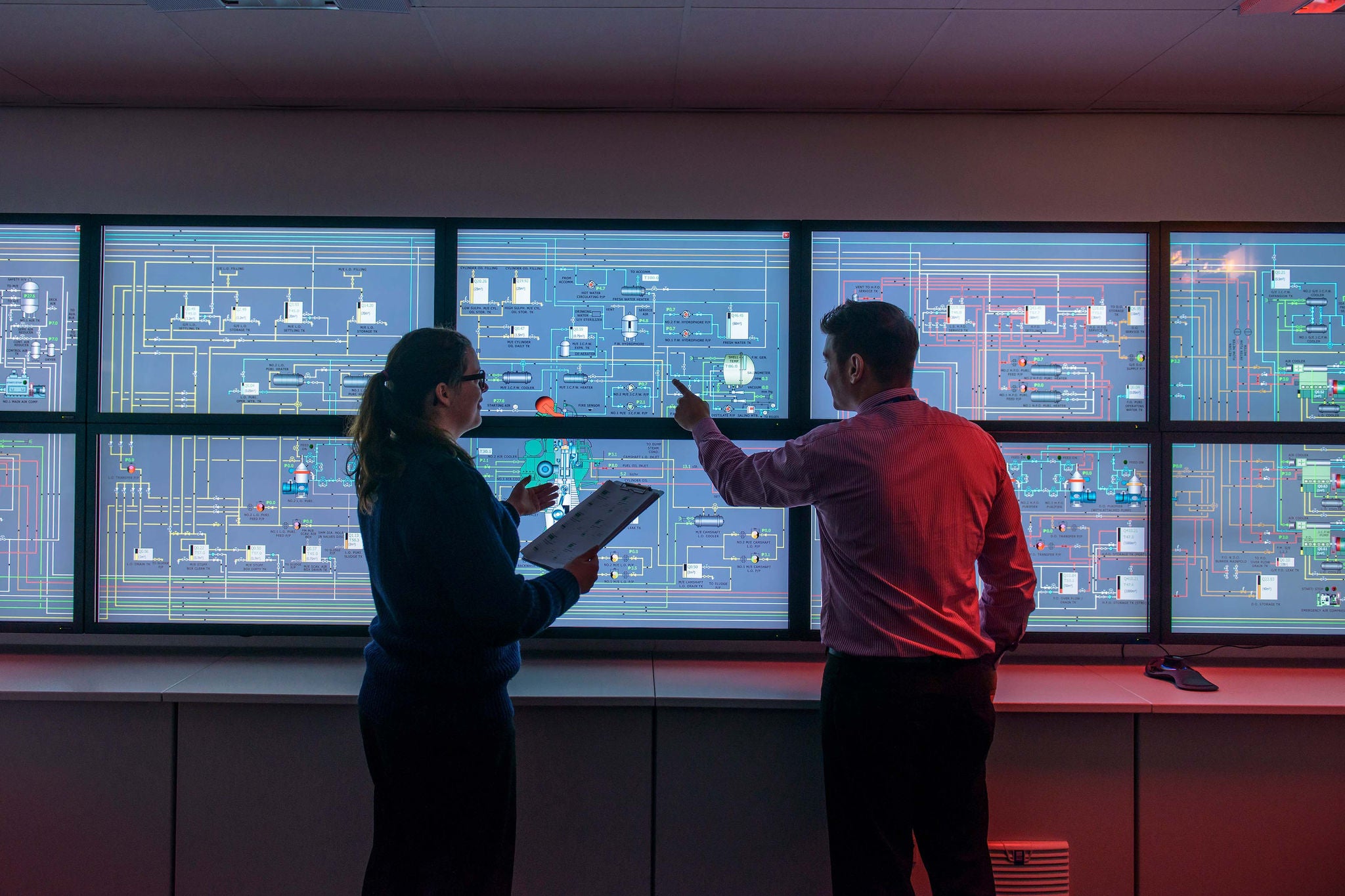 Engineers in front of system monitors on wall background
