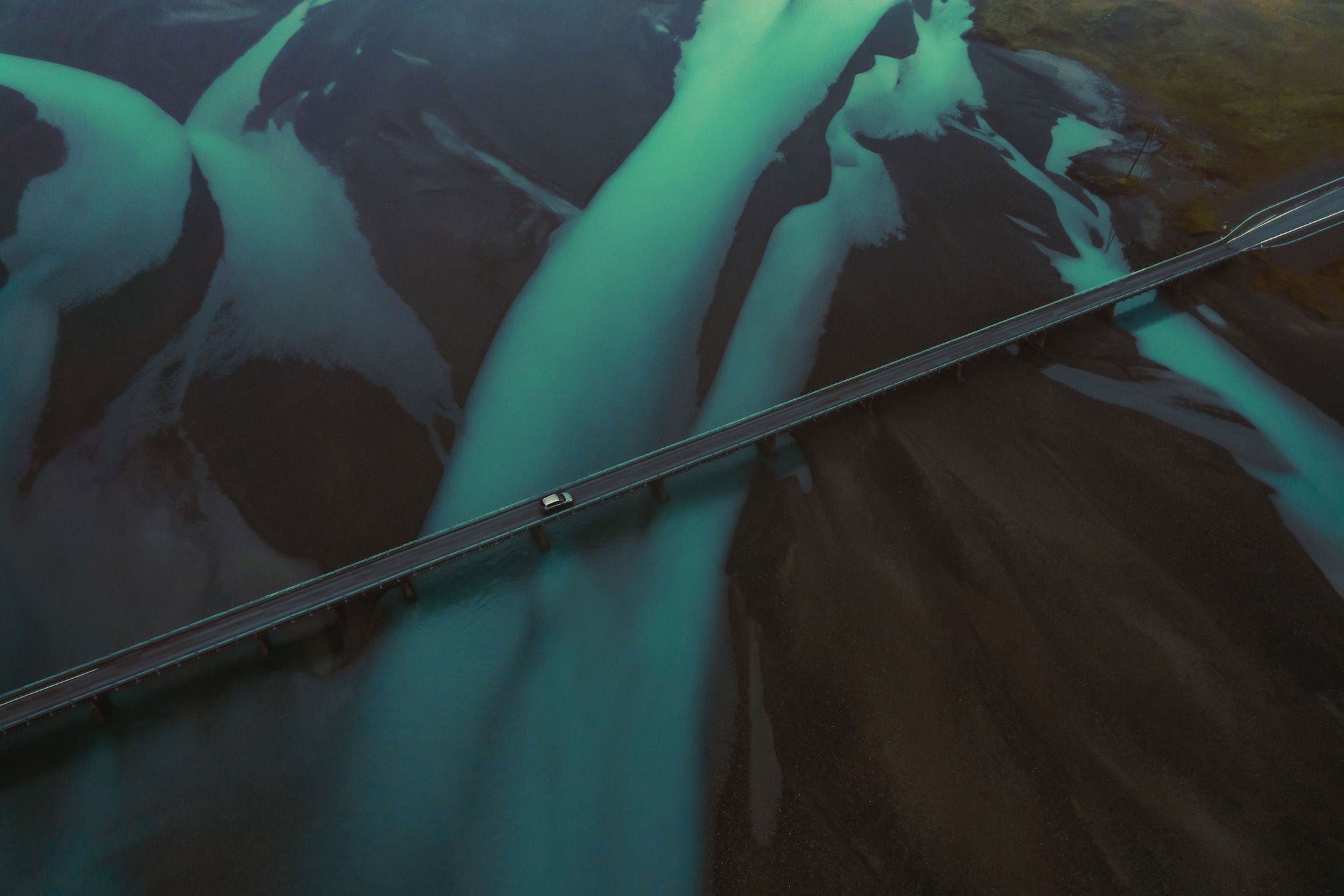 SaT use only Drone view of a car crossing a bridge in Iceland with blue steams of glacier water