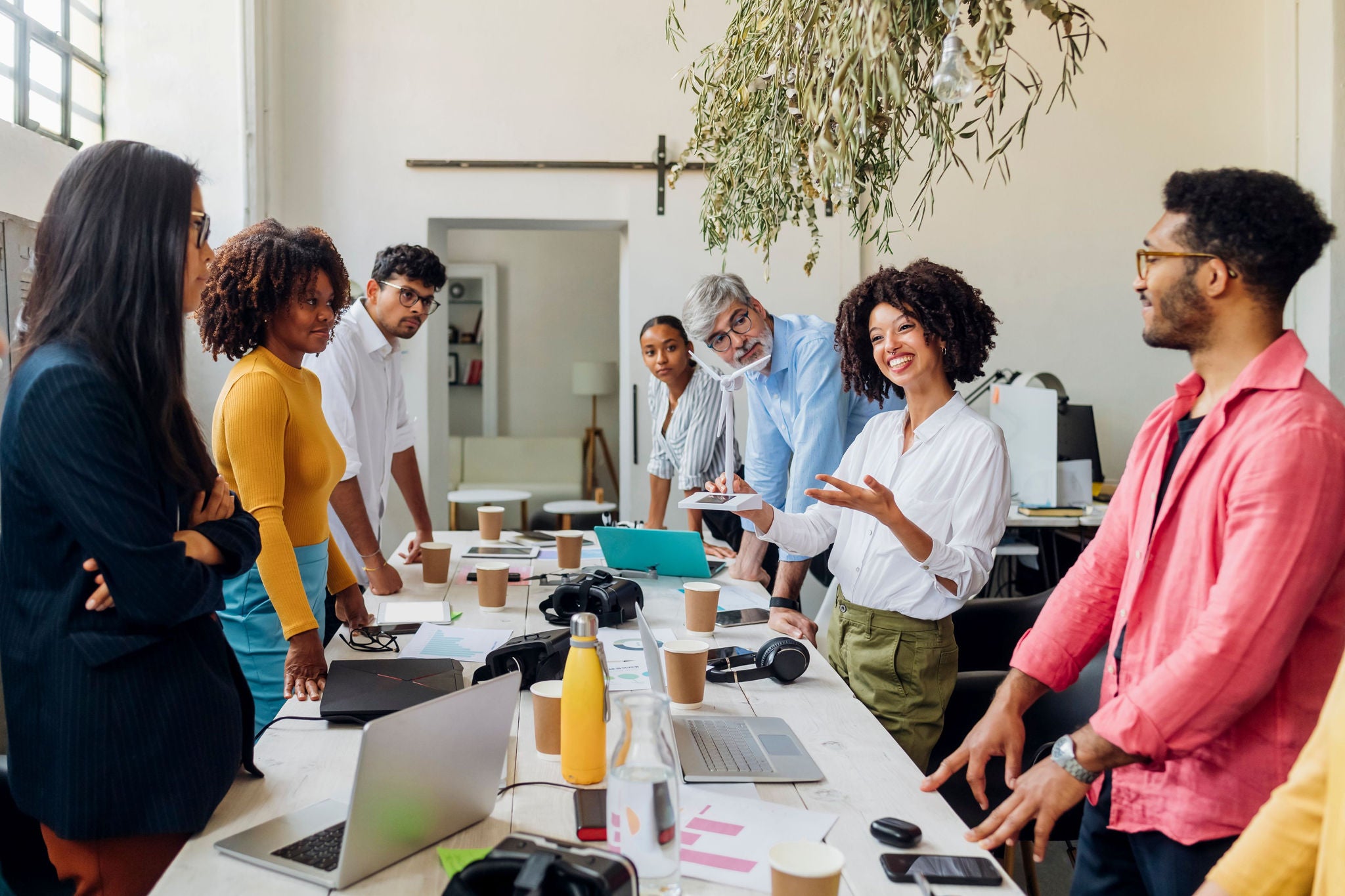 People gathered around a table in a bright workspace, collaborating with laptops and notes.