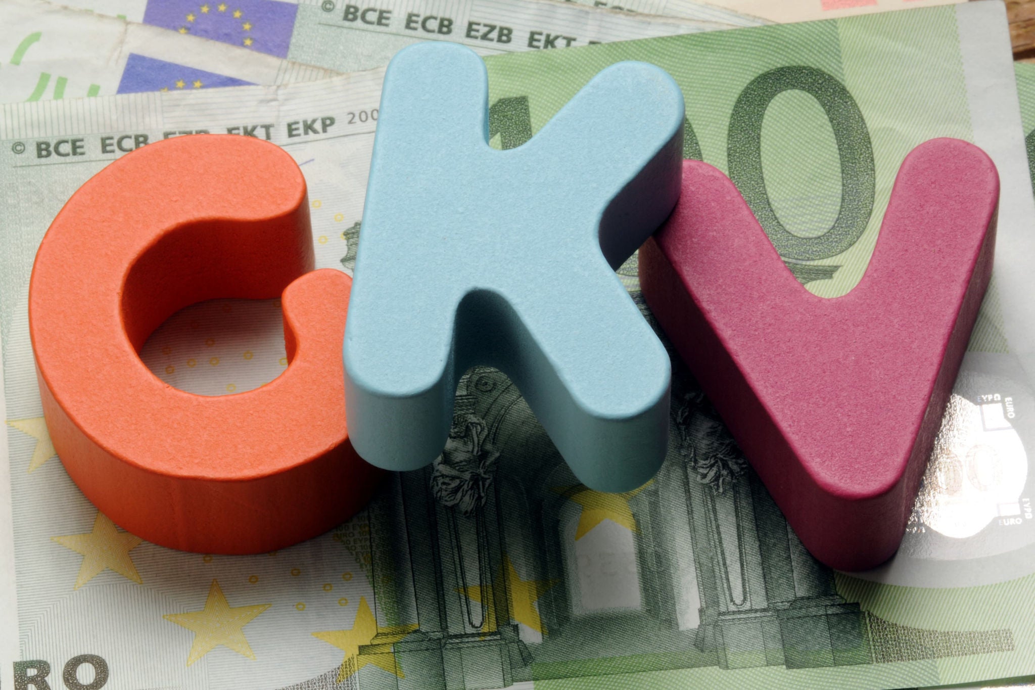 GKV Buchstaben liegen auf Geldscheinen