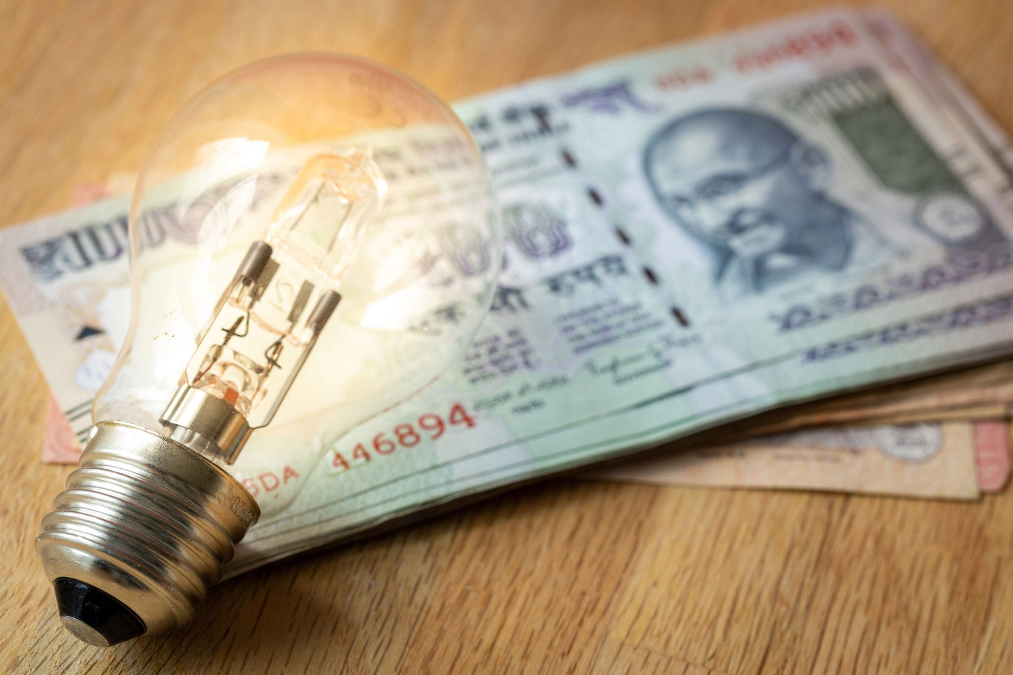 Indian money Lots of rupees and a light bulb, concept of rising energy and electricity prices in India