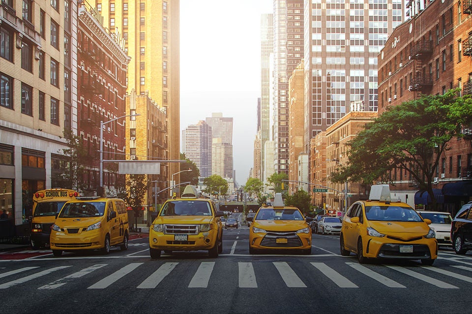 Yellow cabs waiting for green light on the crossroad of streets of New York City during sunny summer daytime