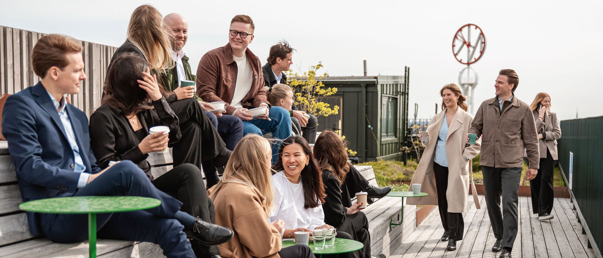 Personer samlade på en träbelagd utomhusyta med bänkar