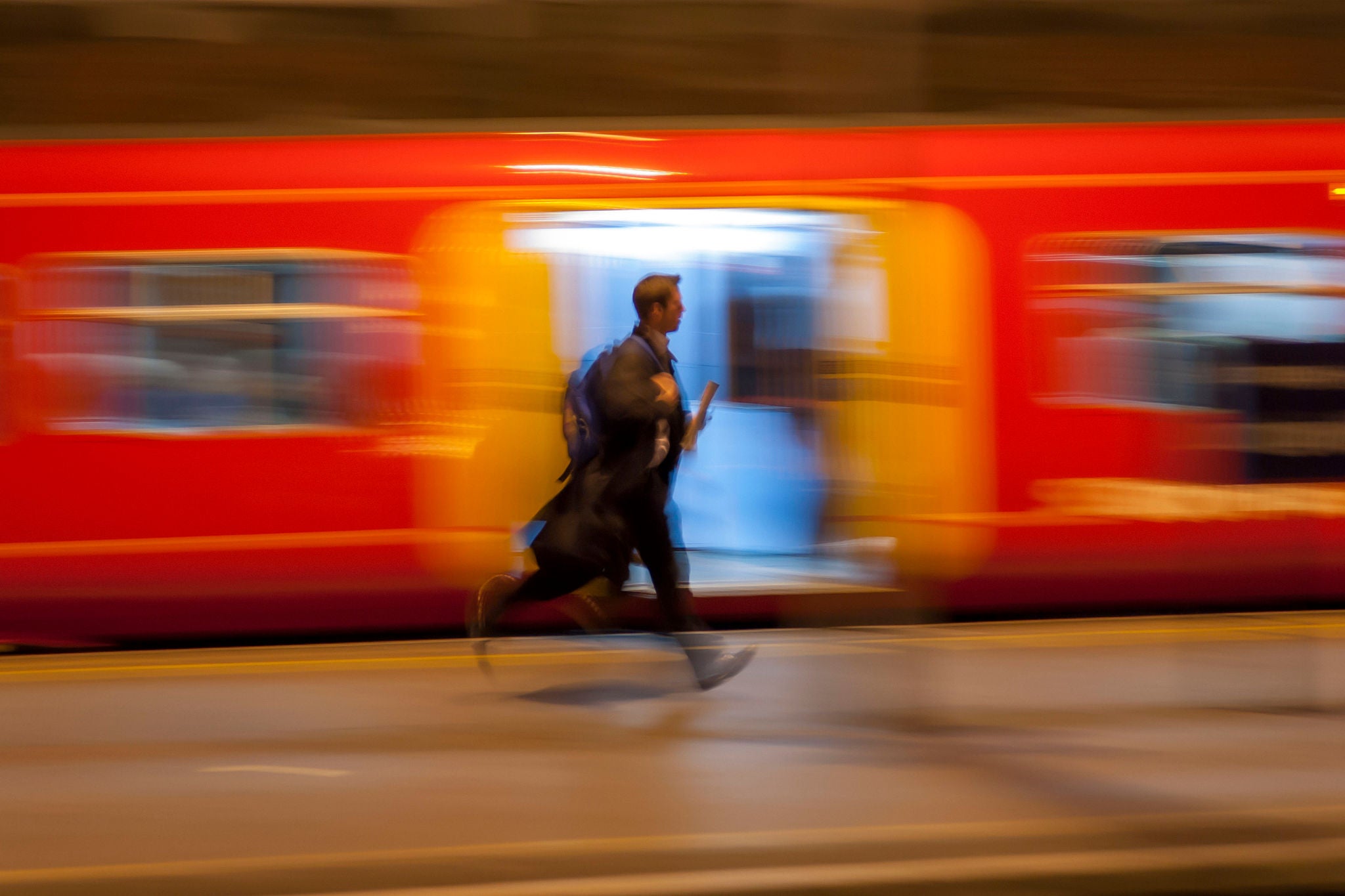 A man runs past a moving train at Paddington station
