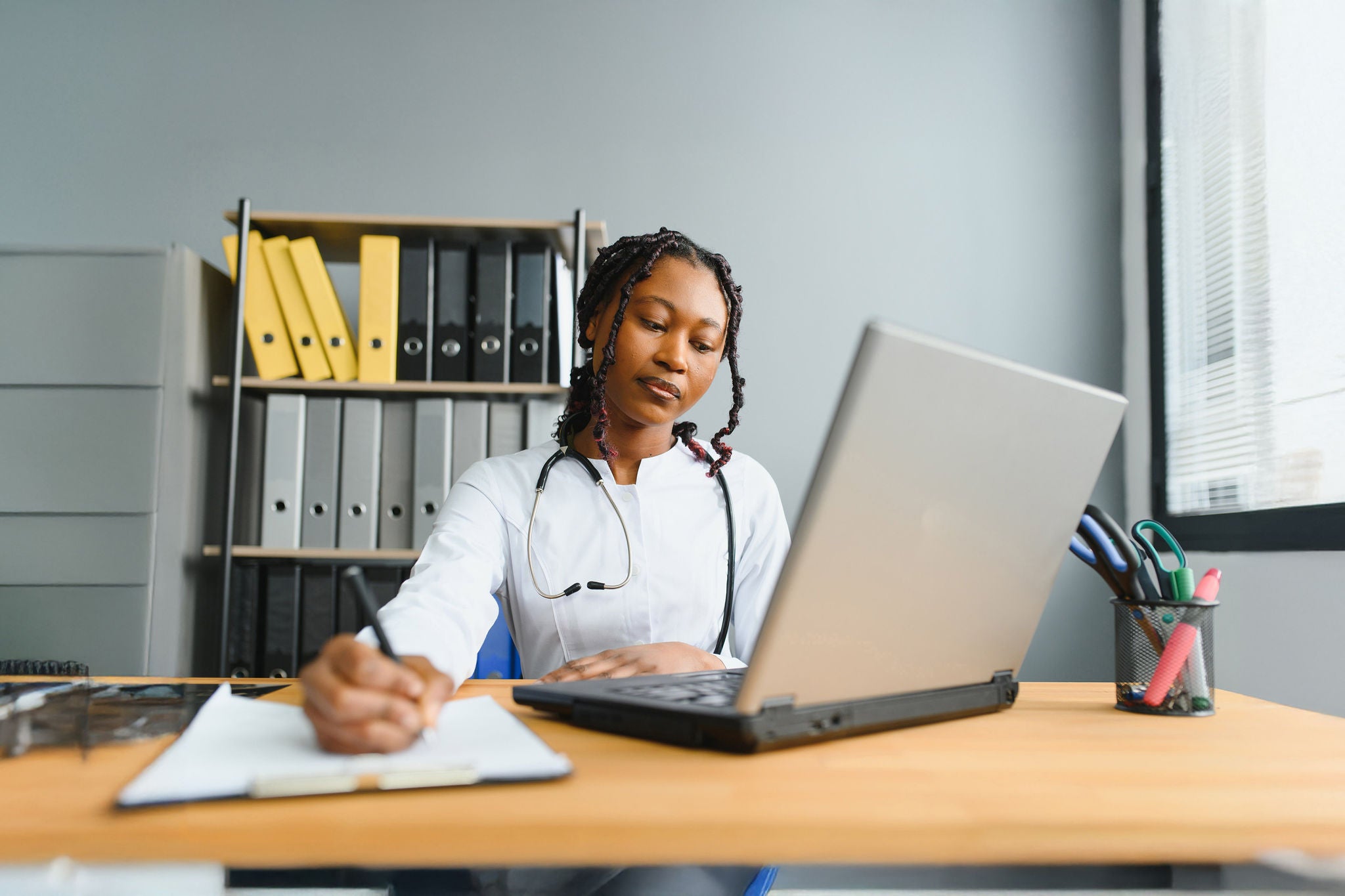 Portrait Of Smiling Female Doctor Wearing White Coat With Stethoscope In Hospital Office