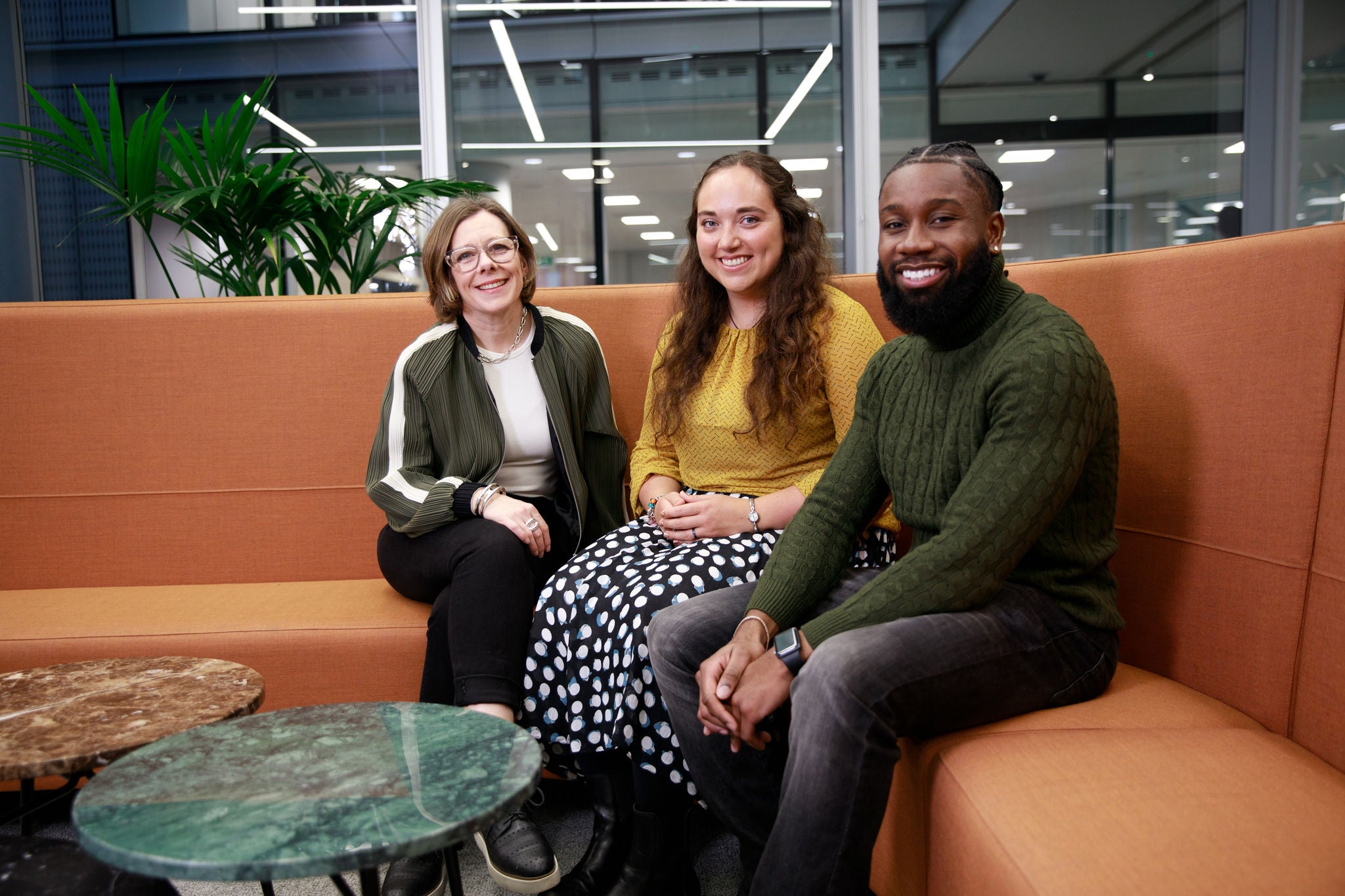 Three colleagues seated together in a modern office lounge