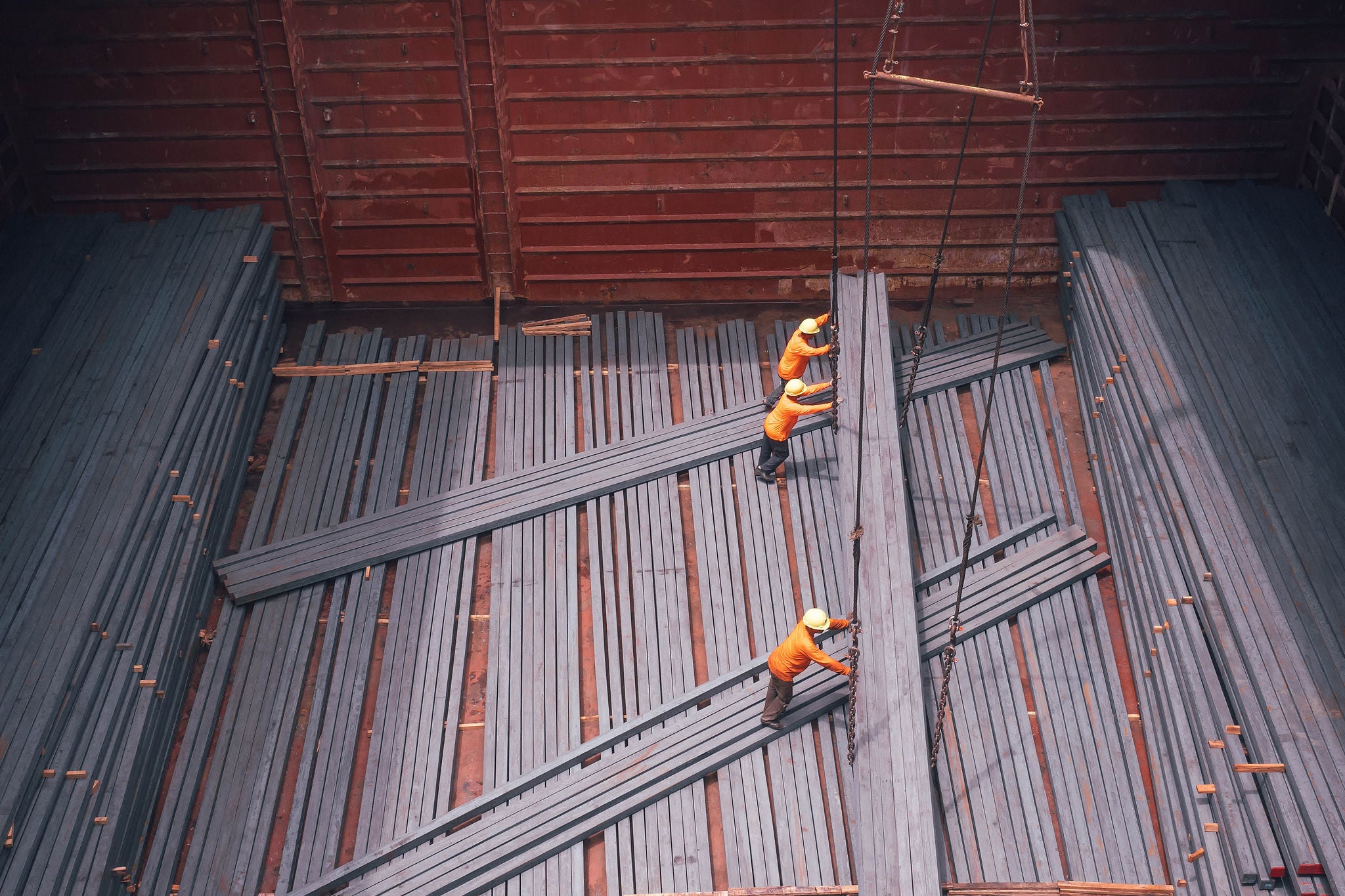  Construction workers lifting steel billets at a port