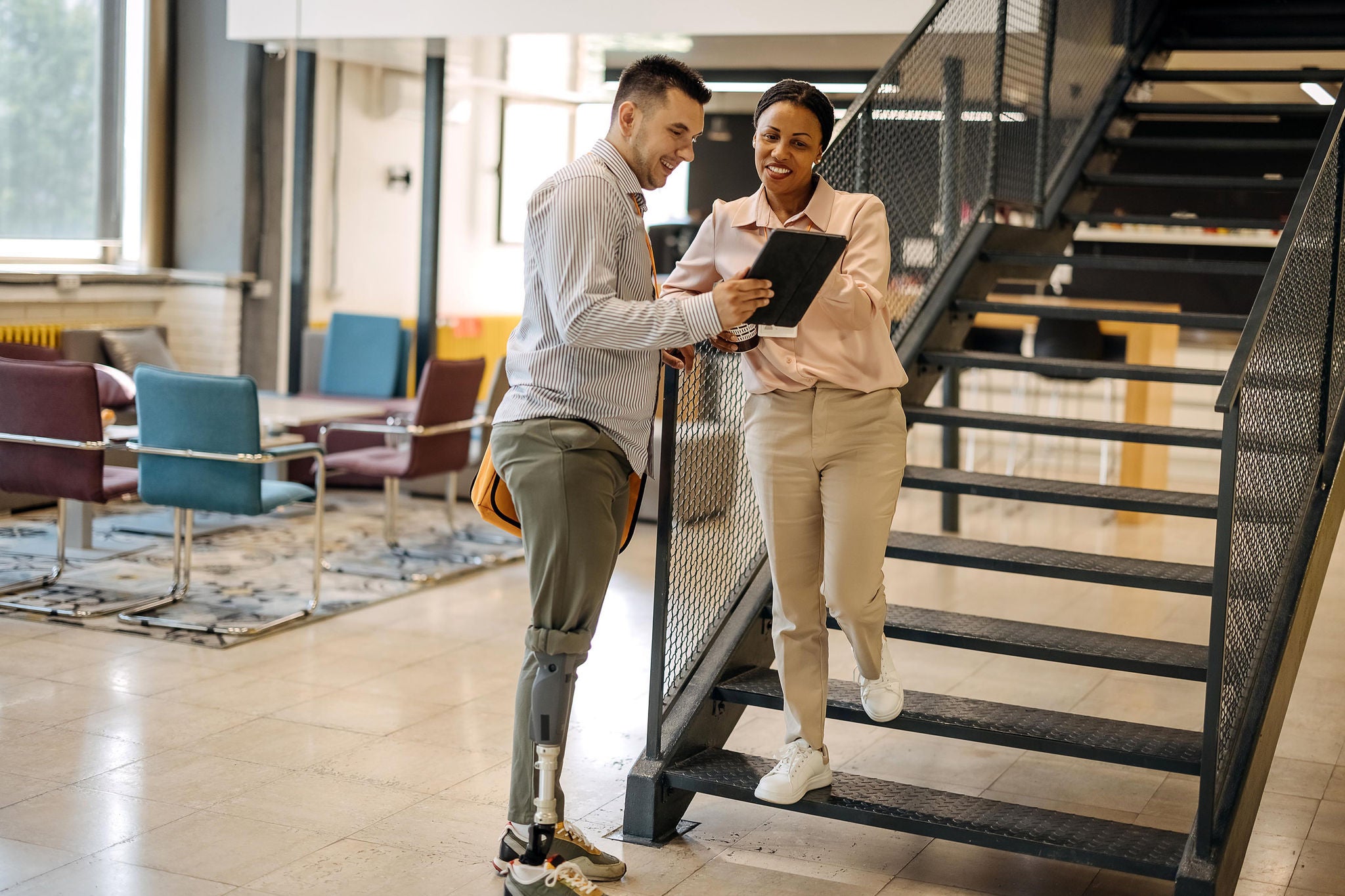 Des-collègues-se-tiennent-dans-le-couloir-et-utilisent-une-tablette-numérique