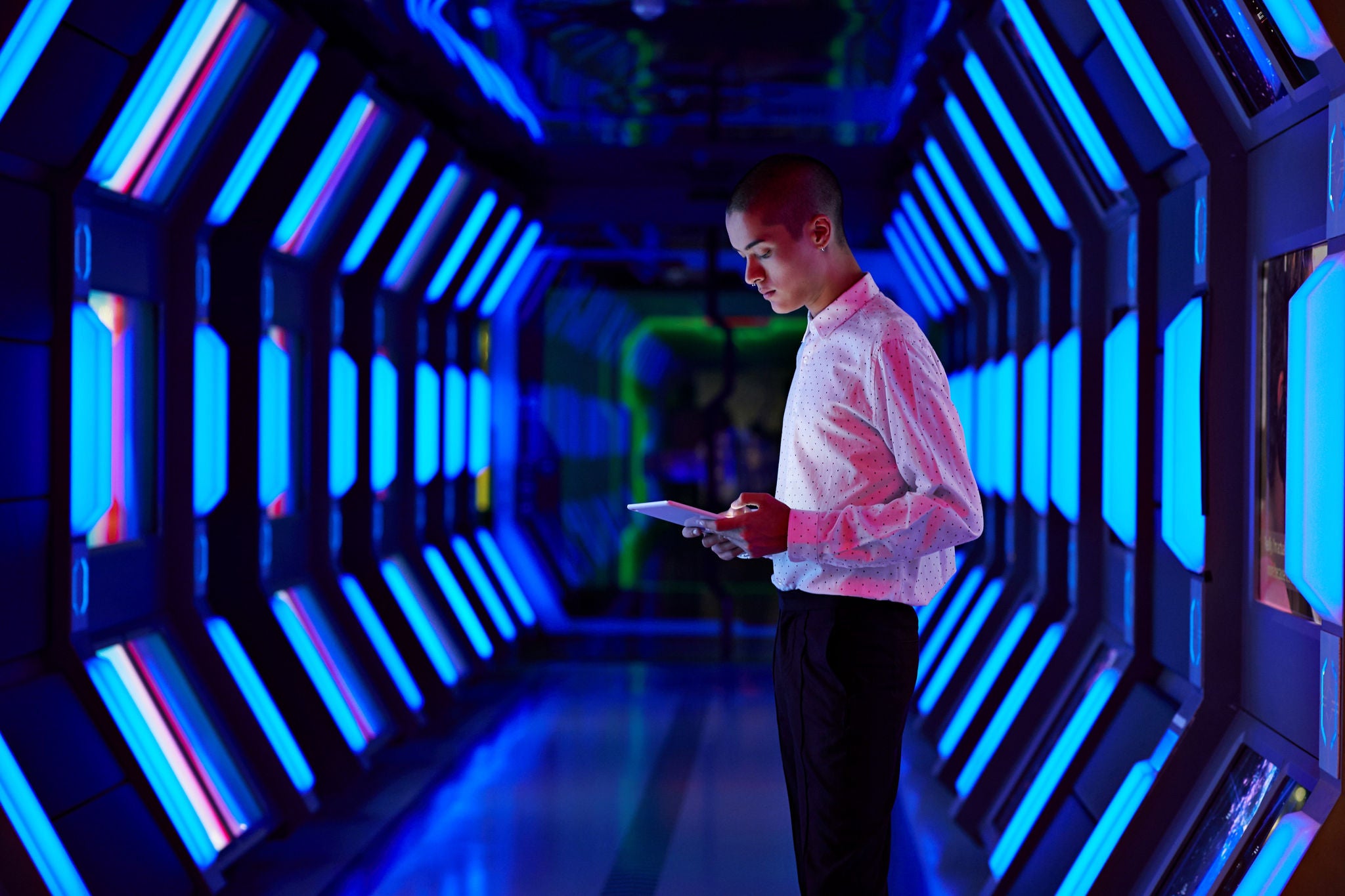 Photo of a man using a tablet inside a futuristic looking tunnel
