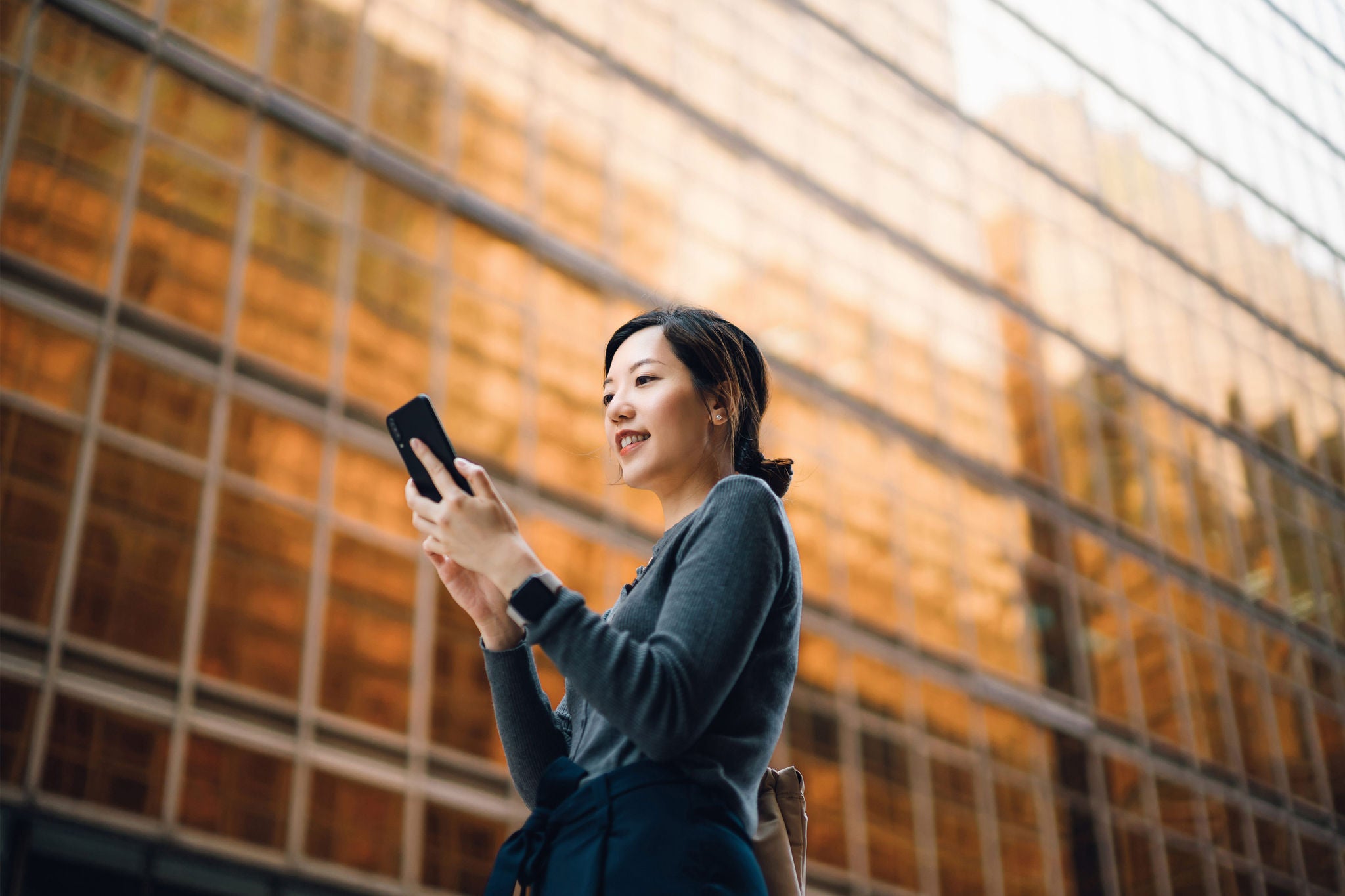Low angle portrait of young asian businesswoman with smartphone on the go