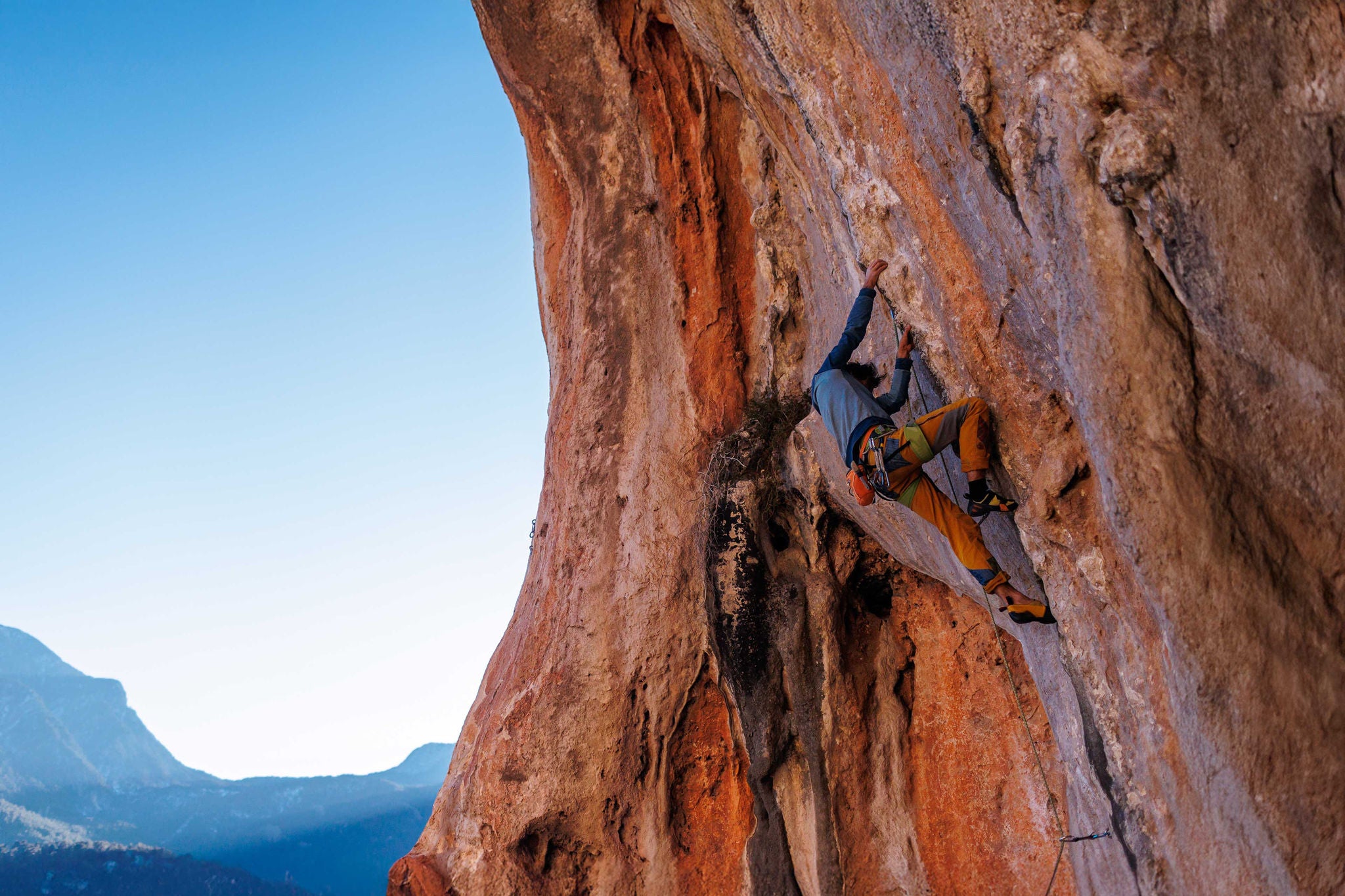 Kletterer steigt eine steile Felswand mit Sicherungsseil hinauf