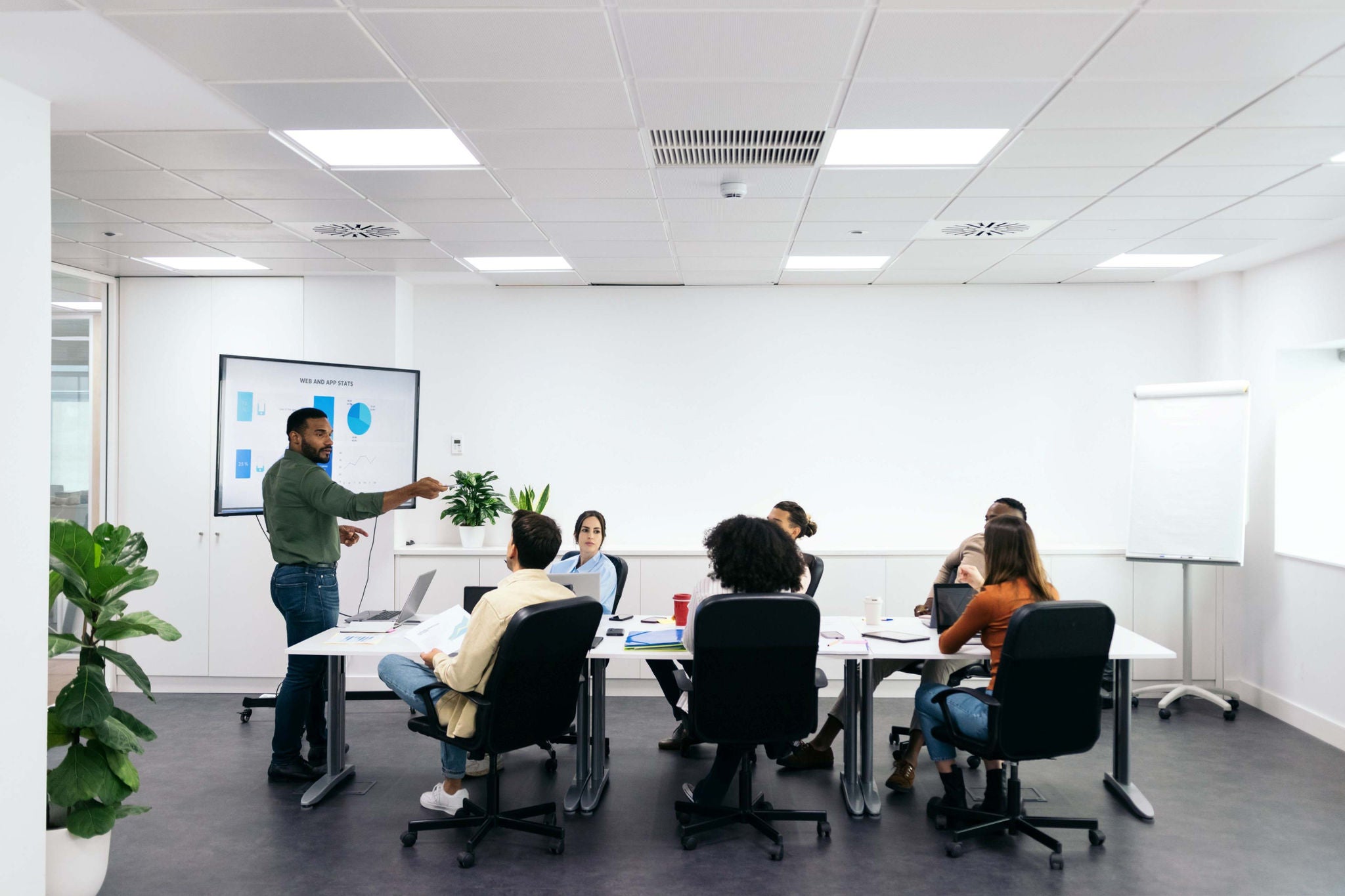 Business presentation in a meeting room with a presenter explaining charts to a team.