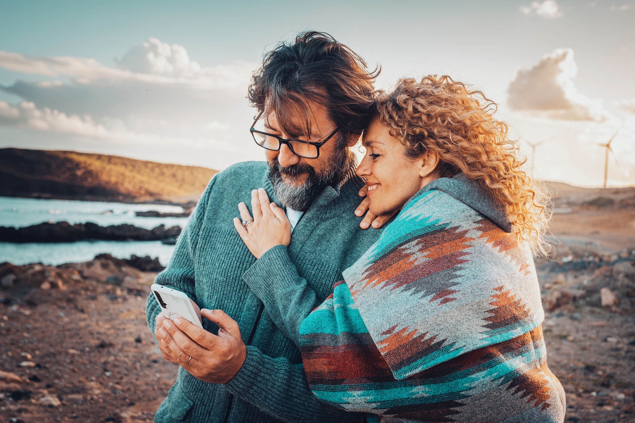 Couple looking at smart phone while taking a walk along the beach