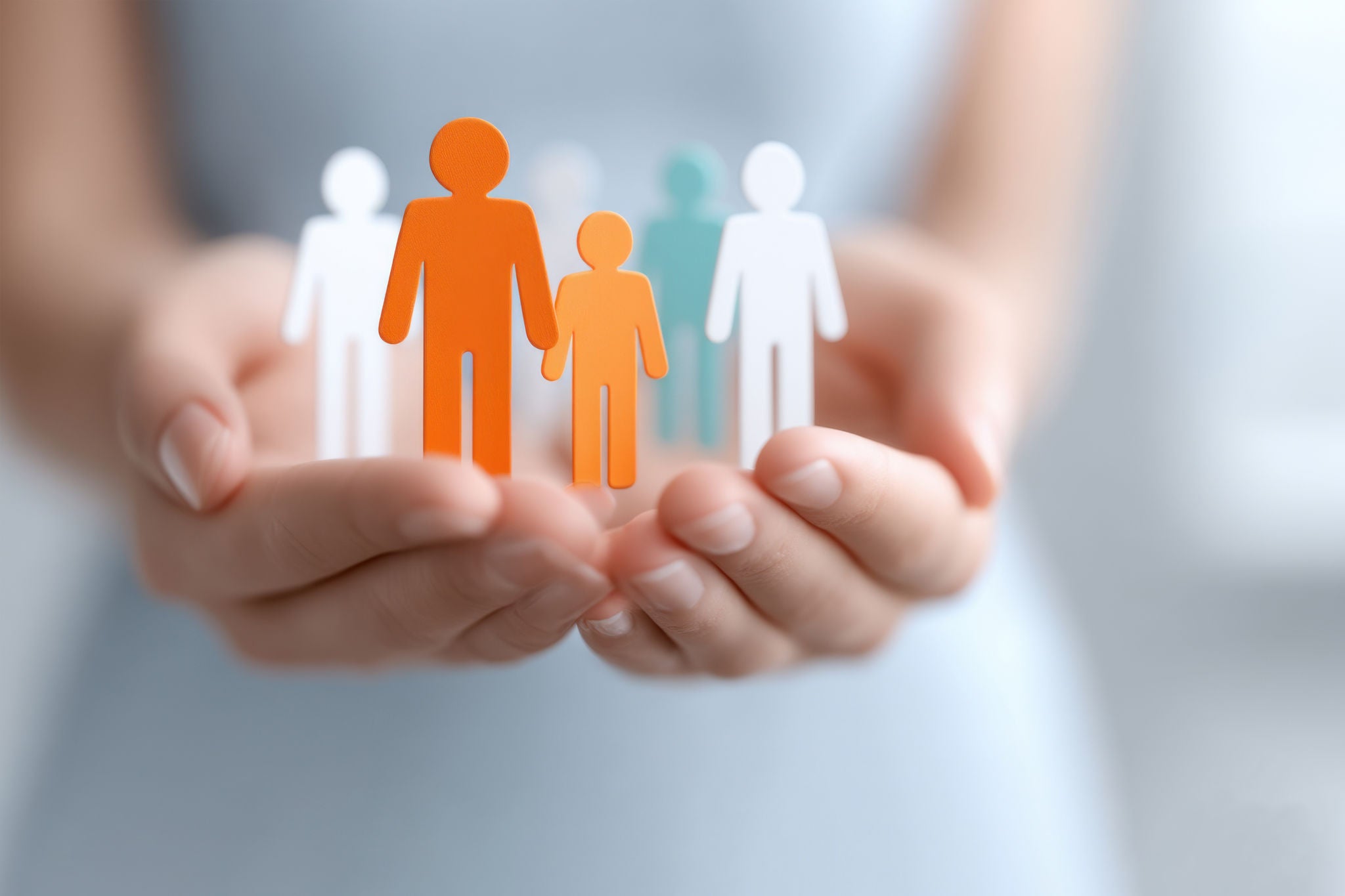 Händer håller figurer som symboliserar familje- och samhällsstöd för att bygga starkare relationer.