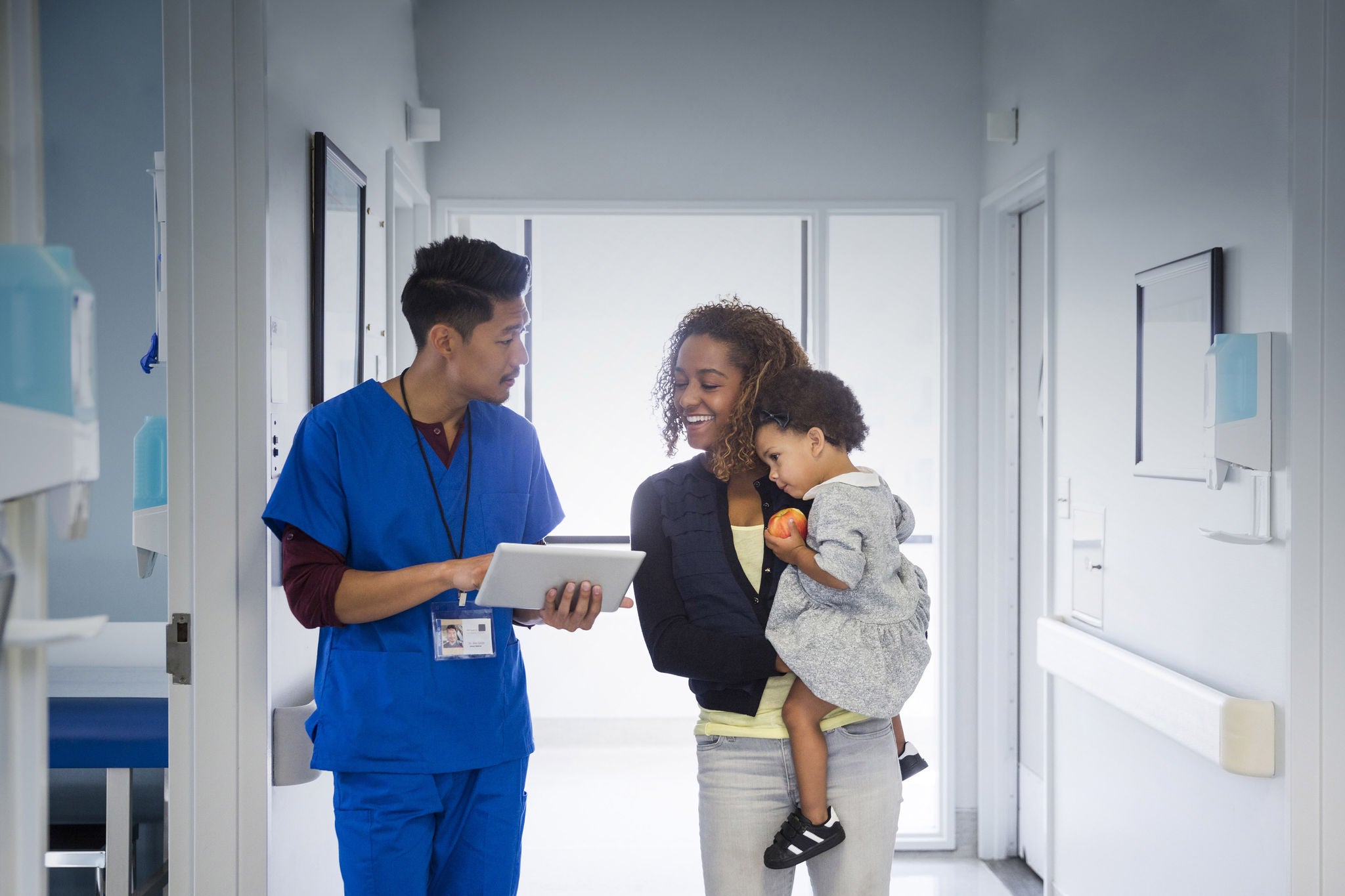 Male nurse talking to mother and baby daughter in hospital corridor, Male nurse talking to mother and baby daughter in hospital corri