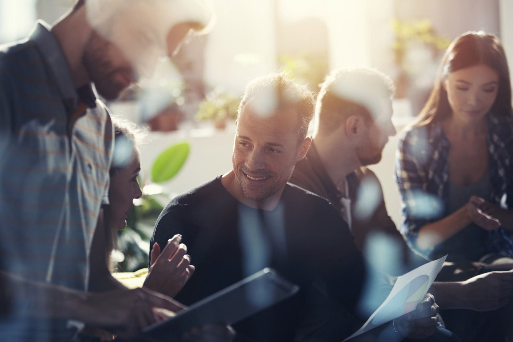 Personas hablando mientras trabajan, se ve de frente a un hombre sonriendo