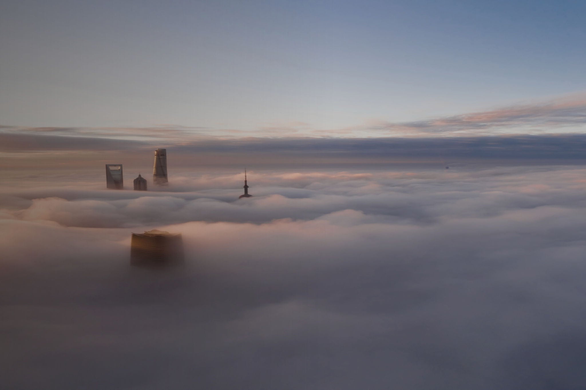 Stadtsilhouette in Deutschland ragt bei Sonnenaufgang über einem dichten Nebelmeer mit modernen Hochhäusern